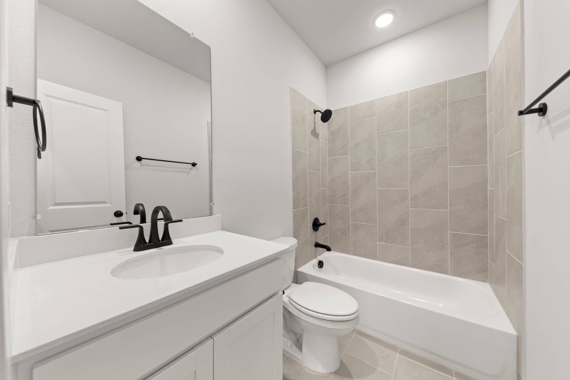 Modern bathroom with sleek fixtures, white vanity, and tiled bathtub area.