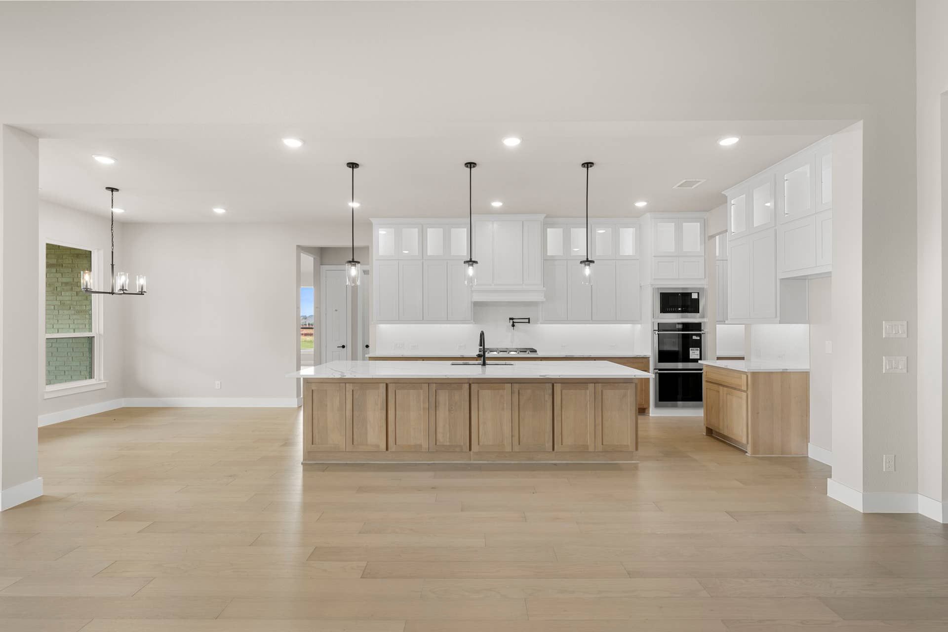 Spacious modern kitchen with white cabinetry and wood accents.