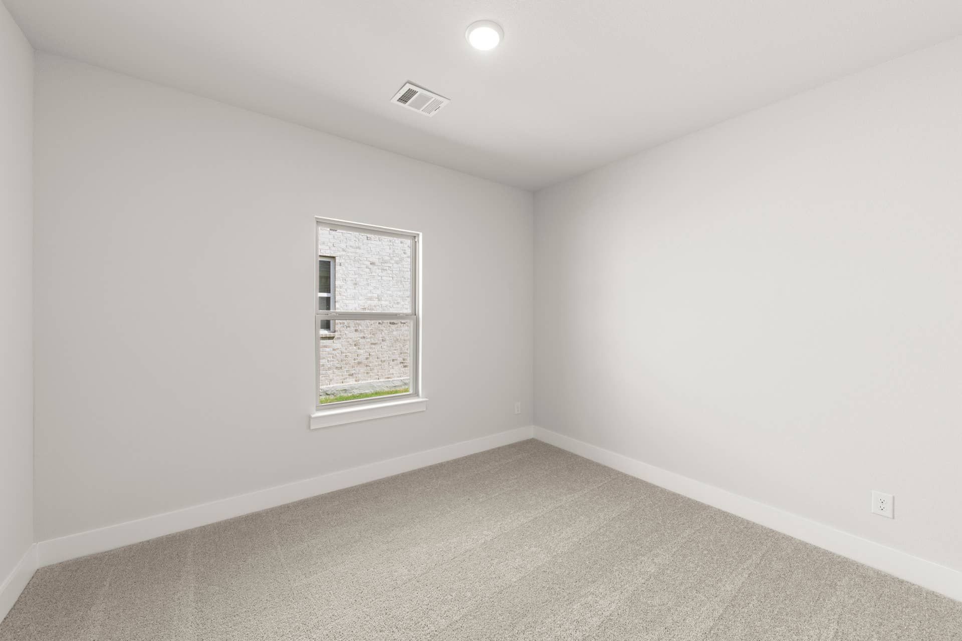 Minimalist bedroom with neutral carpet and single window.