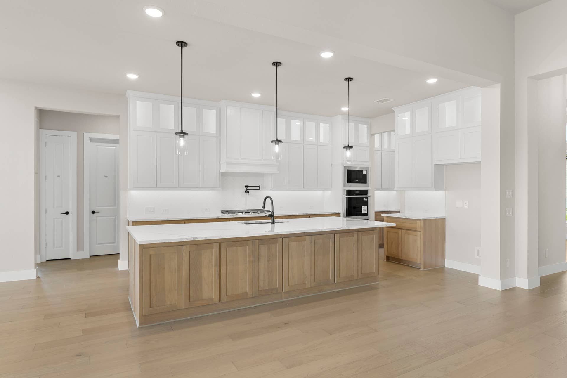 Spacious modern kitchen with white cabinetry, wood island, and pendant lighting.