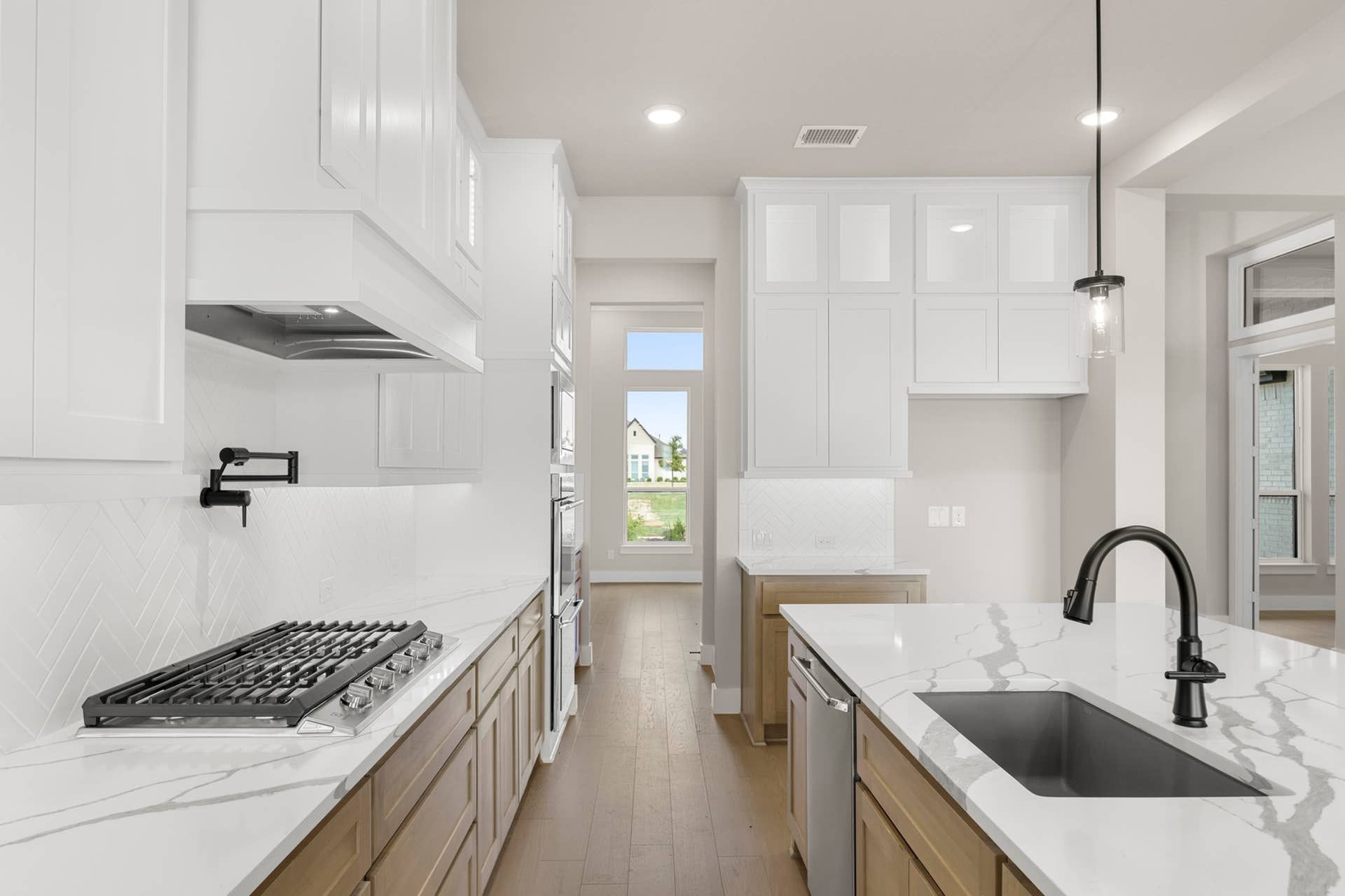Modern kitchen with white cabinetry, marble countertops, and stainless steel appliances.