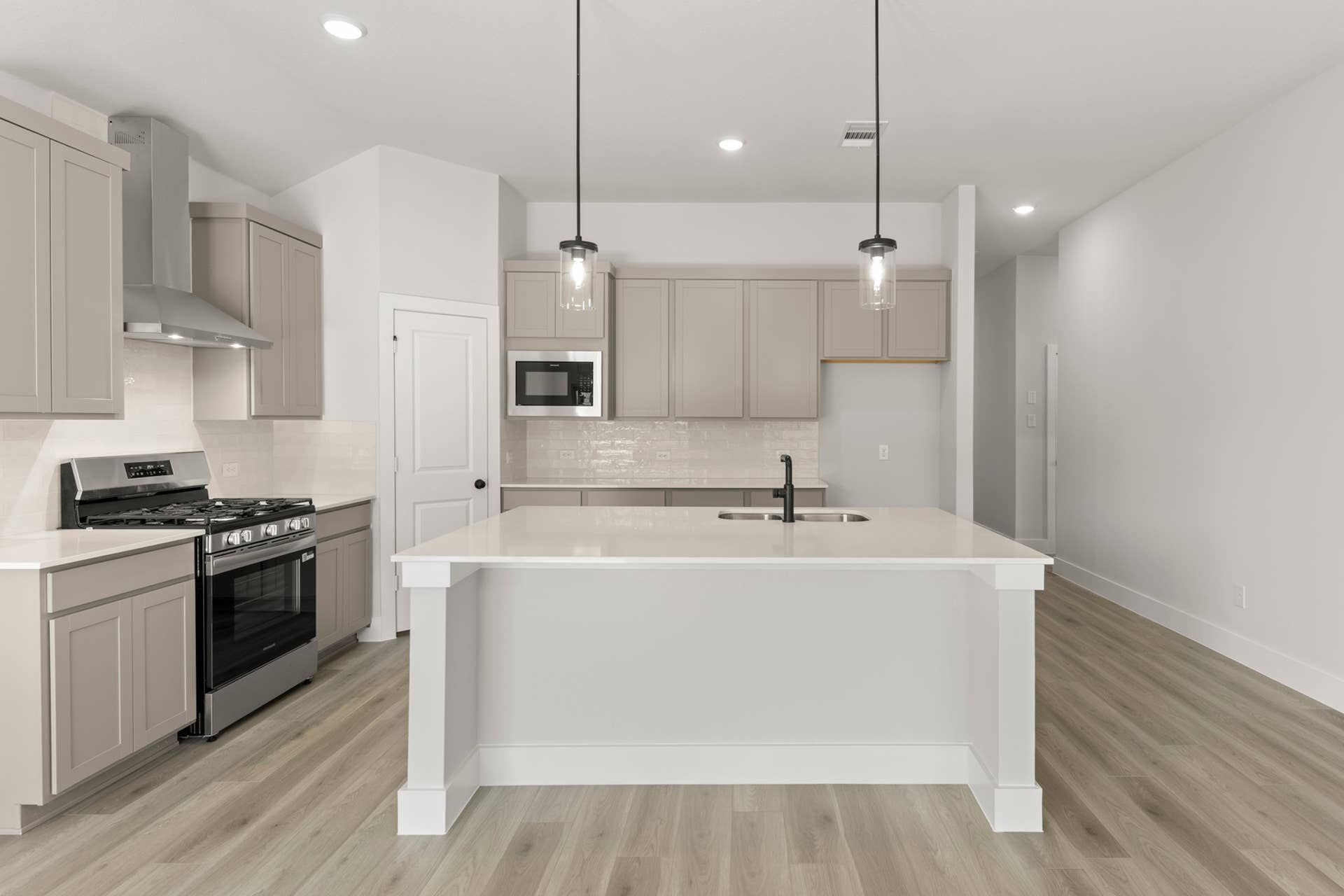 Modern kitchen with island, stainless steel appliances, and pendant lighting.