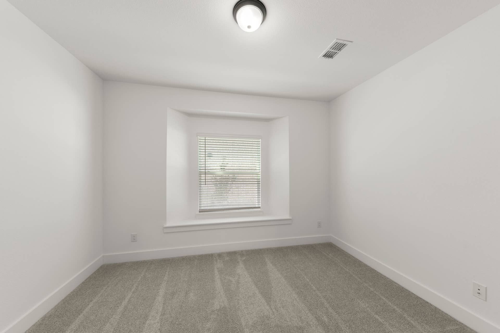 Bright study room with carpet flooring and a recessed window.