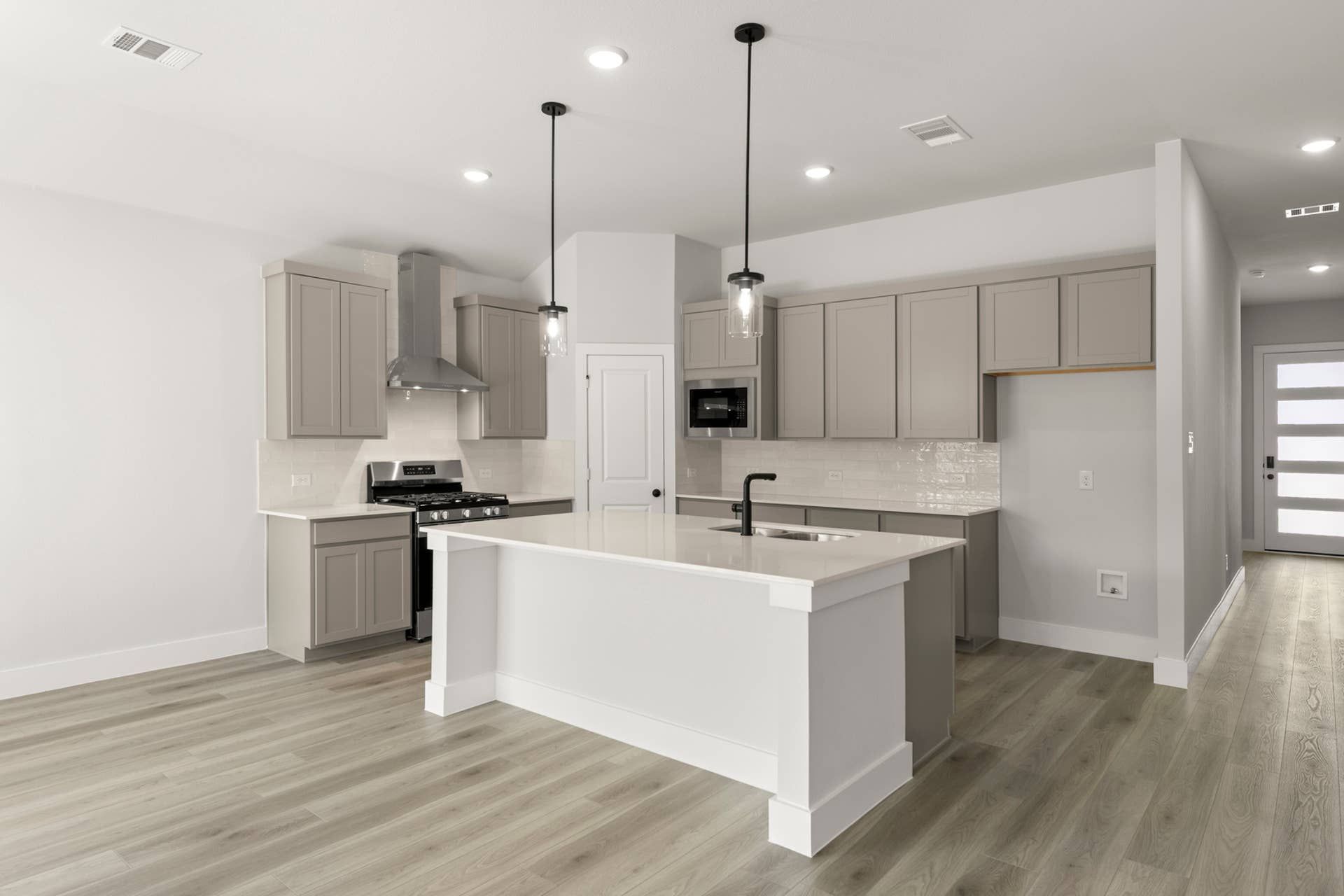 Modern kitchen with island, pendant lights, and sleek gray cabinetry.