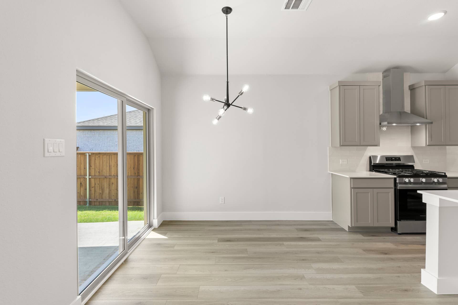 Modern kitchen and dining area with sliding glass doors and stylish light fixture.