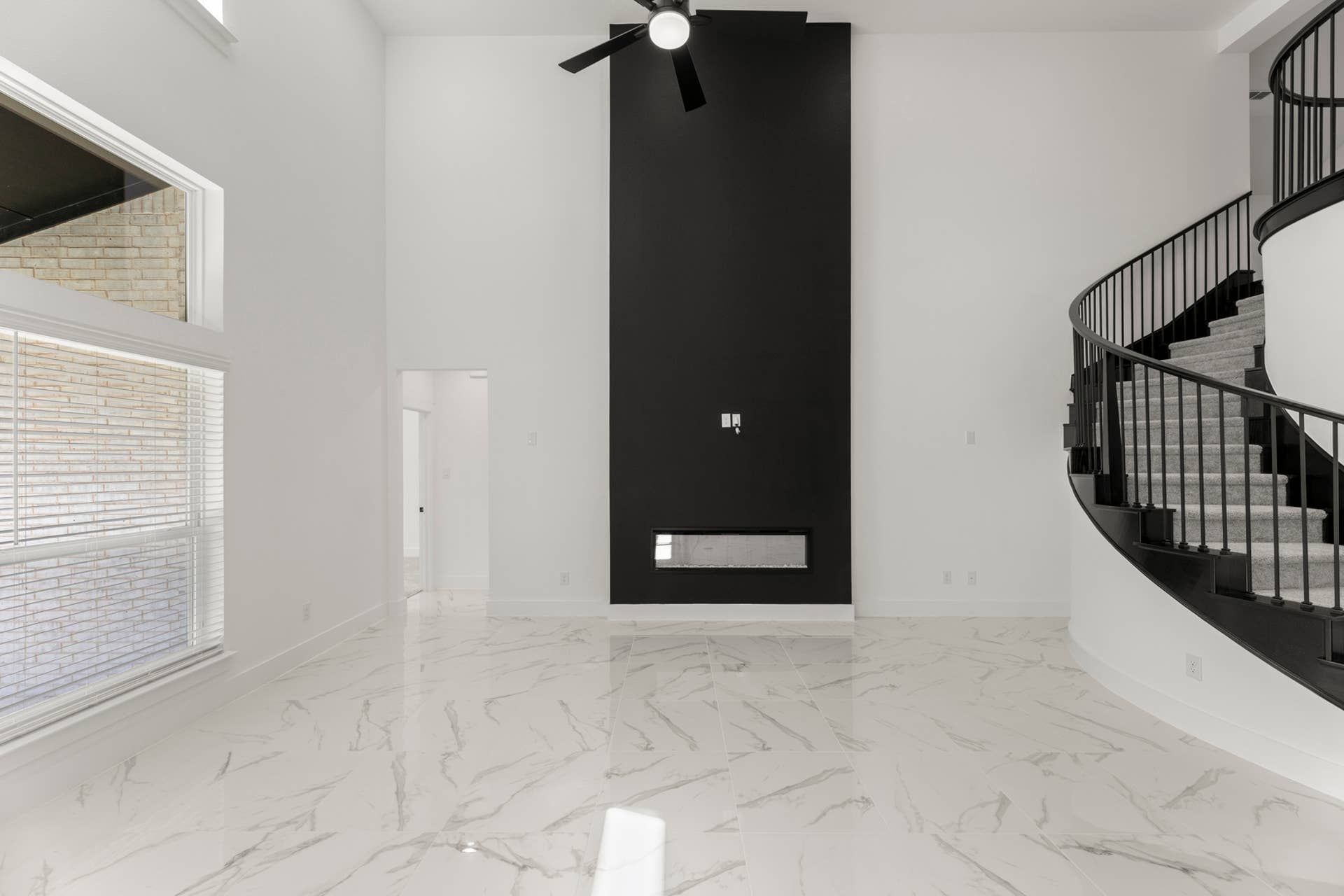 Spacious modern interior with marble floors, black accent wall, and curved staircase.