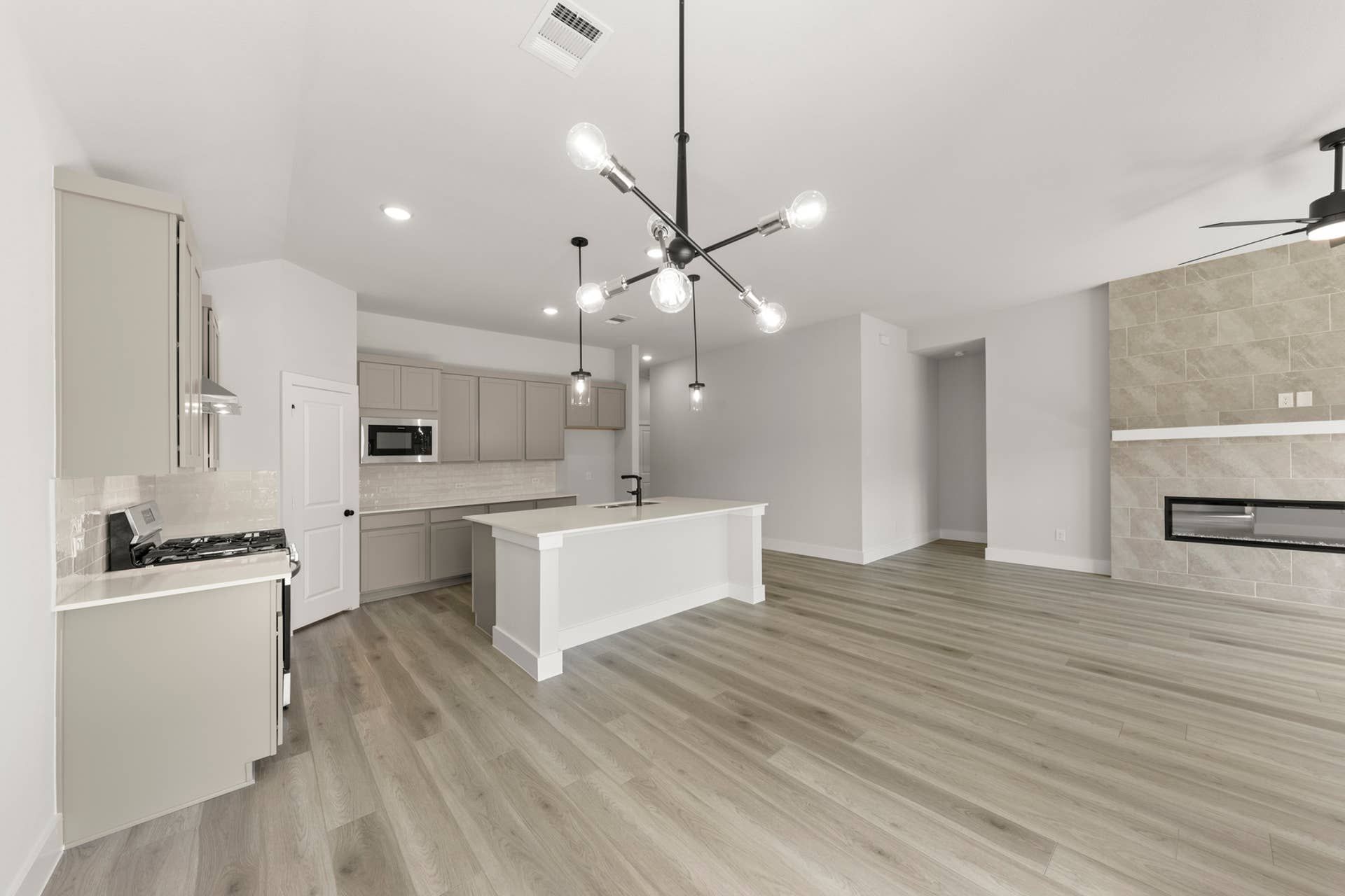 Modern open-plan kitchen and dining area with sleek lighting and hardwood floors.