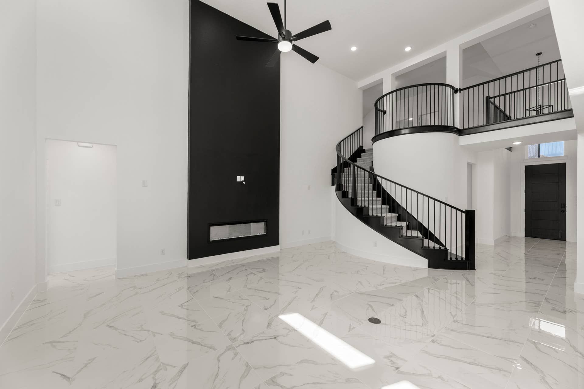 Modern interior with spiral staircase, high ceiling, and black accent wall.