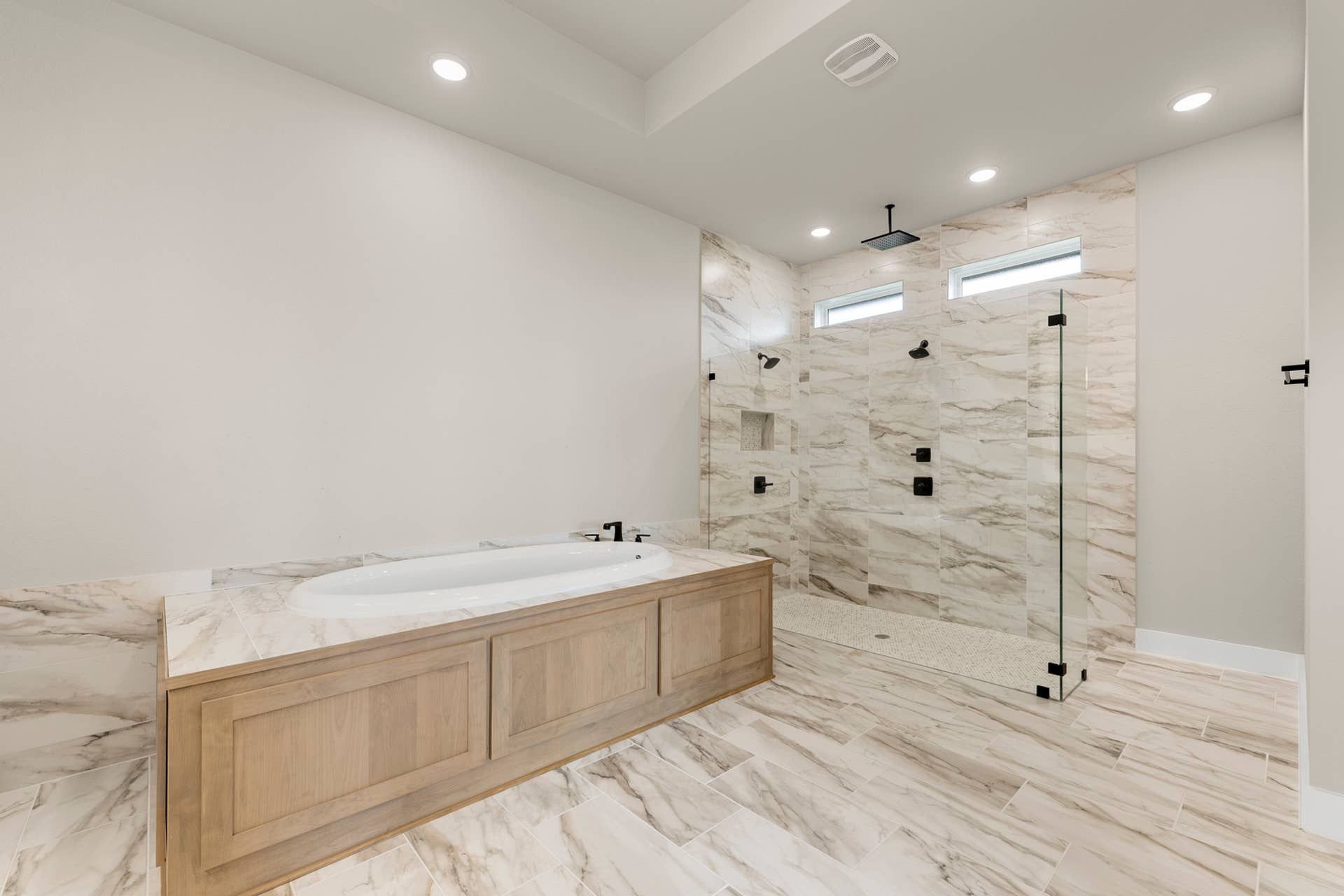 Luxurious bathroom with marble tiles, glass shower, and built-in bathtub.