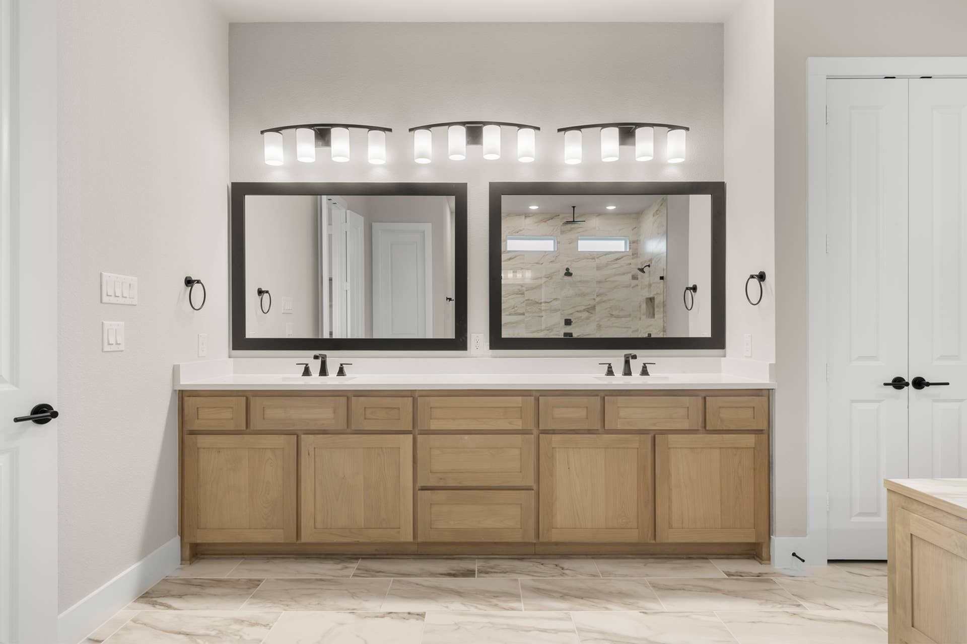 Modern bathroom with dual sinks, wooden cabinets, and large mirrors.