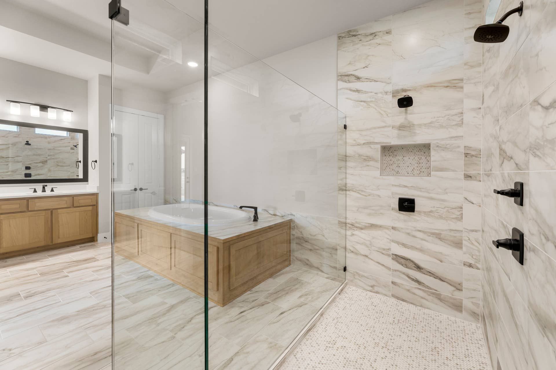 Luxurious bathroom with marble tiles, glass shower, and wooden vanity.