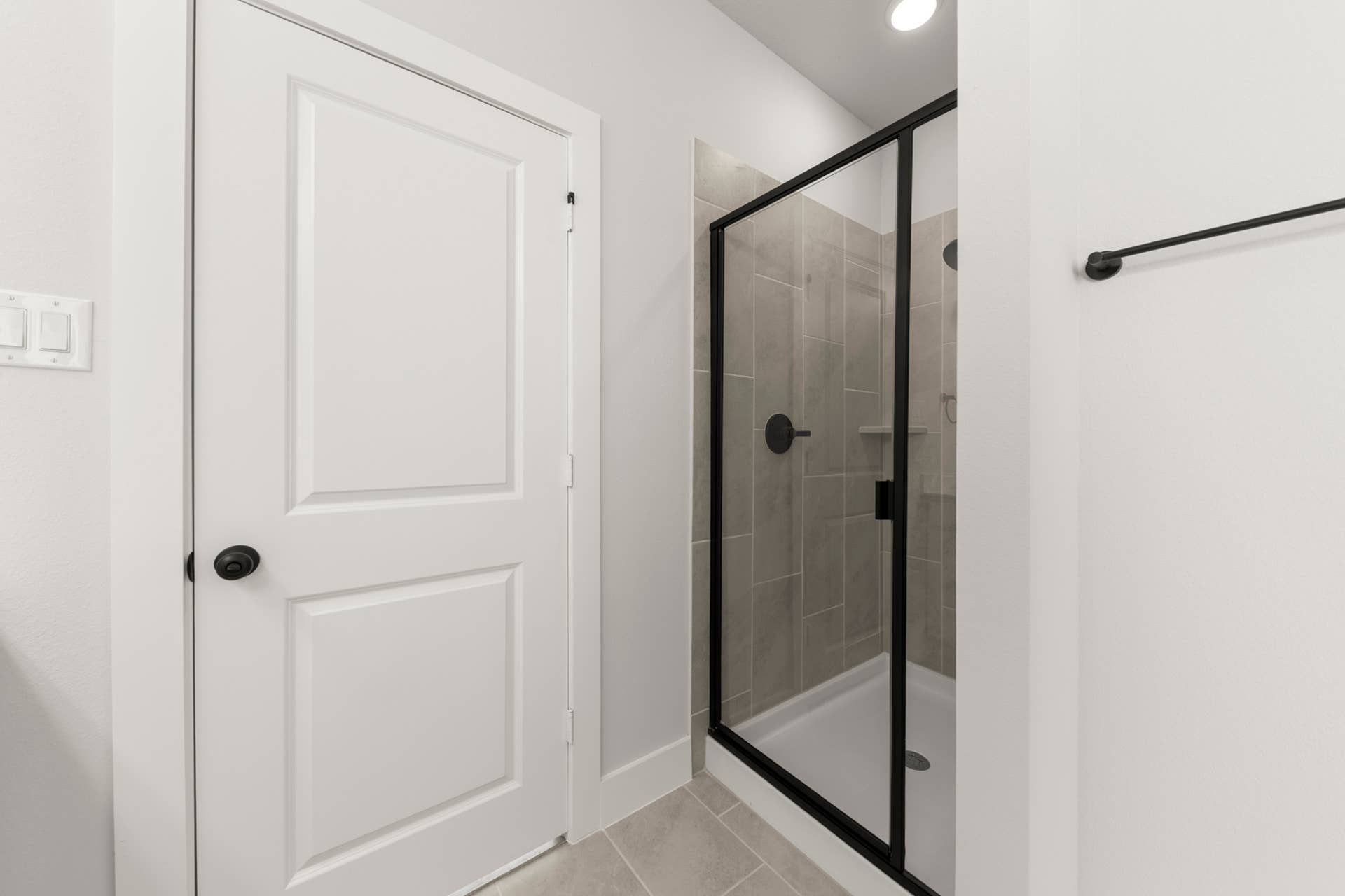 Modern bathroom with glass shower and white door.