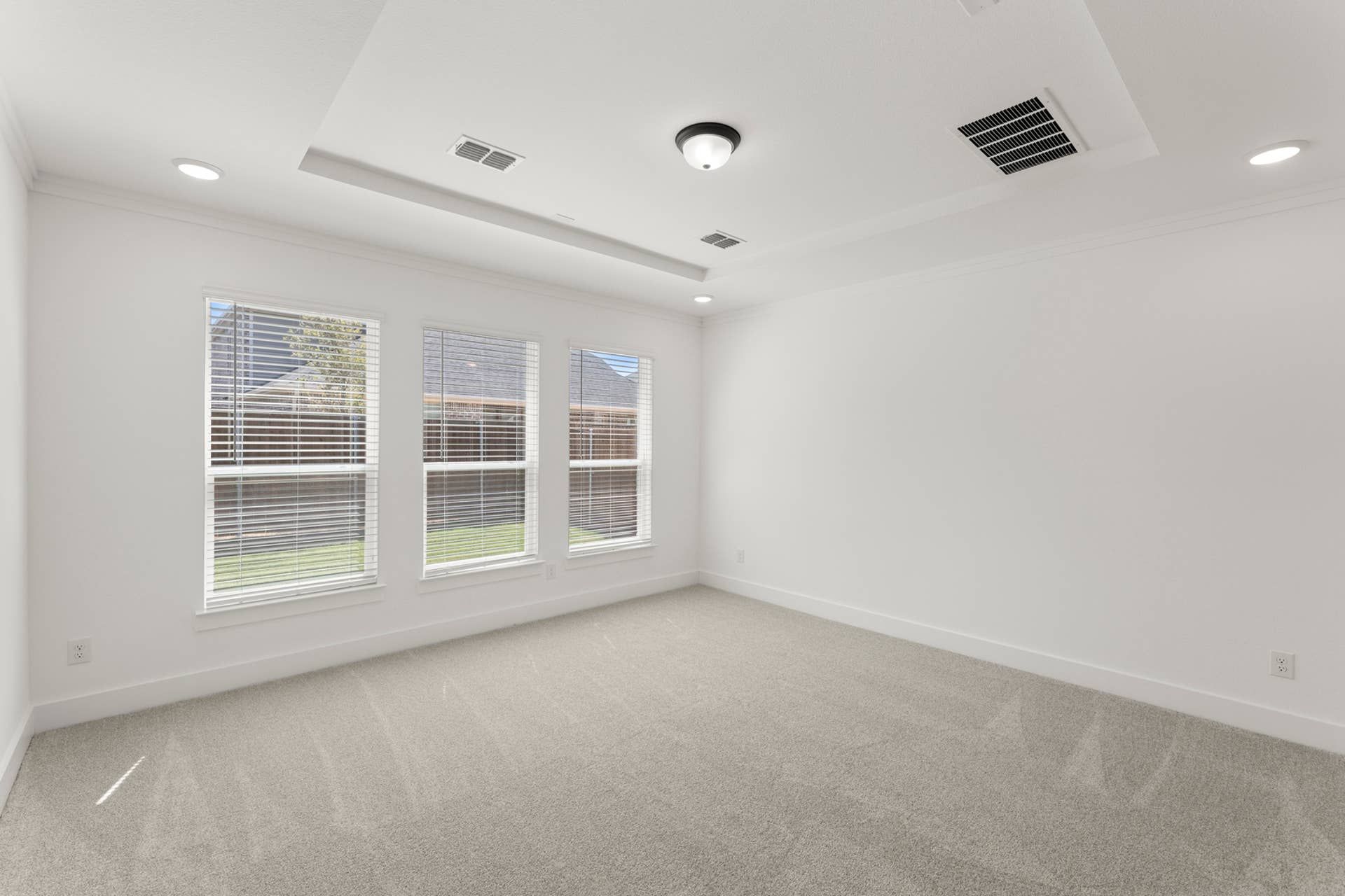 Spacious interior room with large windows and recessed lighting.