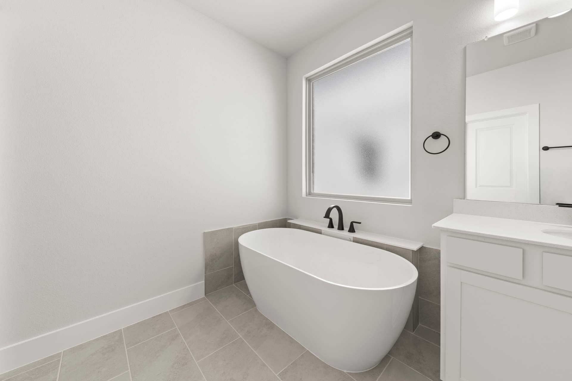 Modern bathroom with freestanding tub and frosted window.