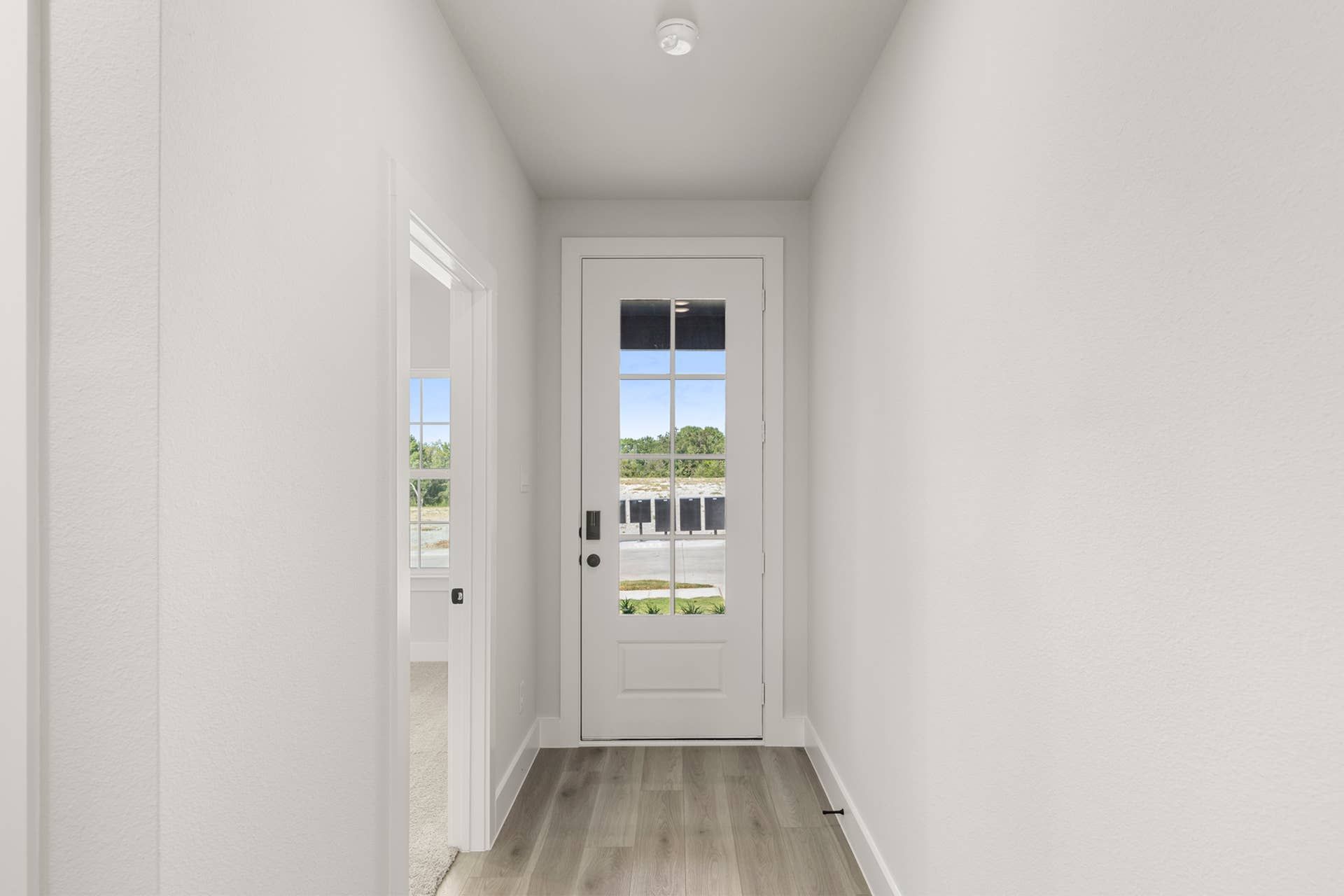 Bright entryway with glass door and wood flooring.