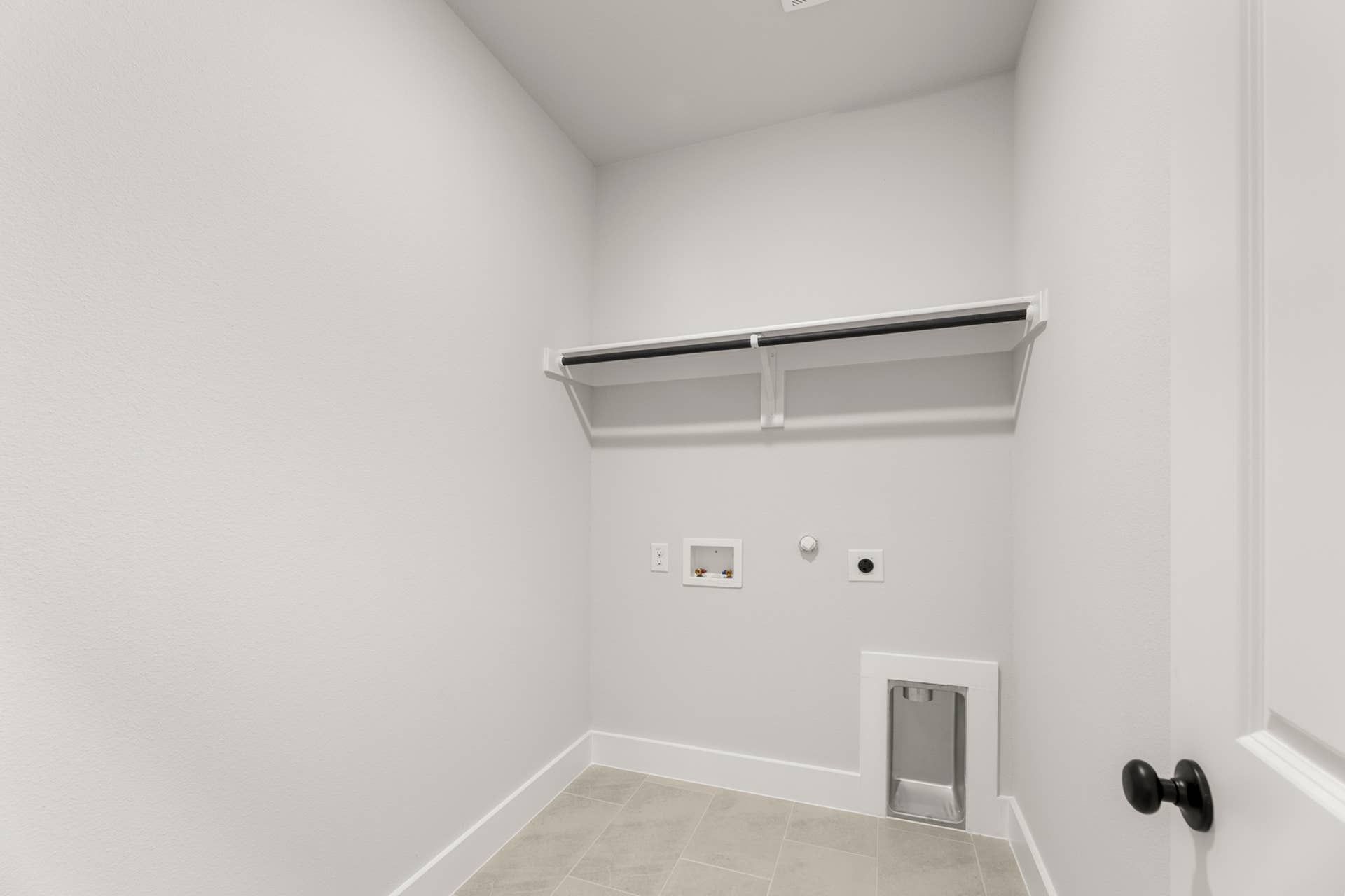 Utility room with white walls, shelf, and washer-dryer hookups.