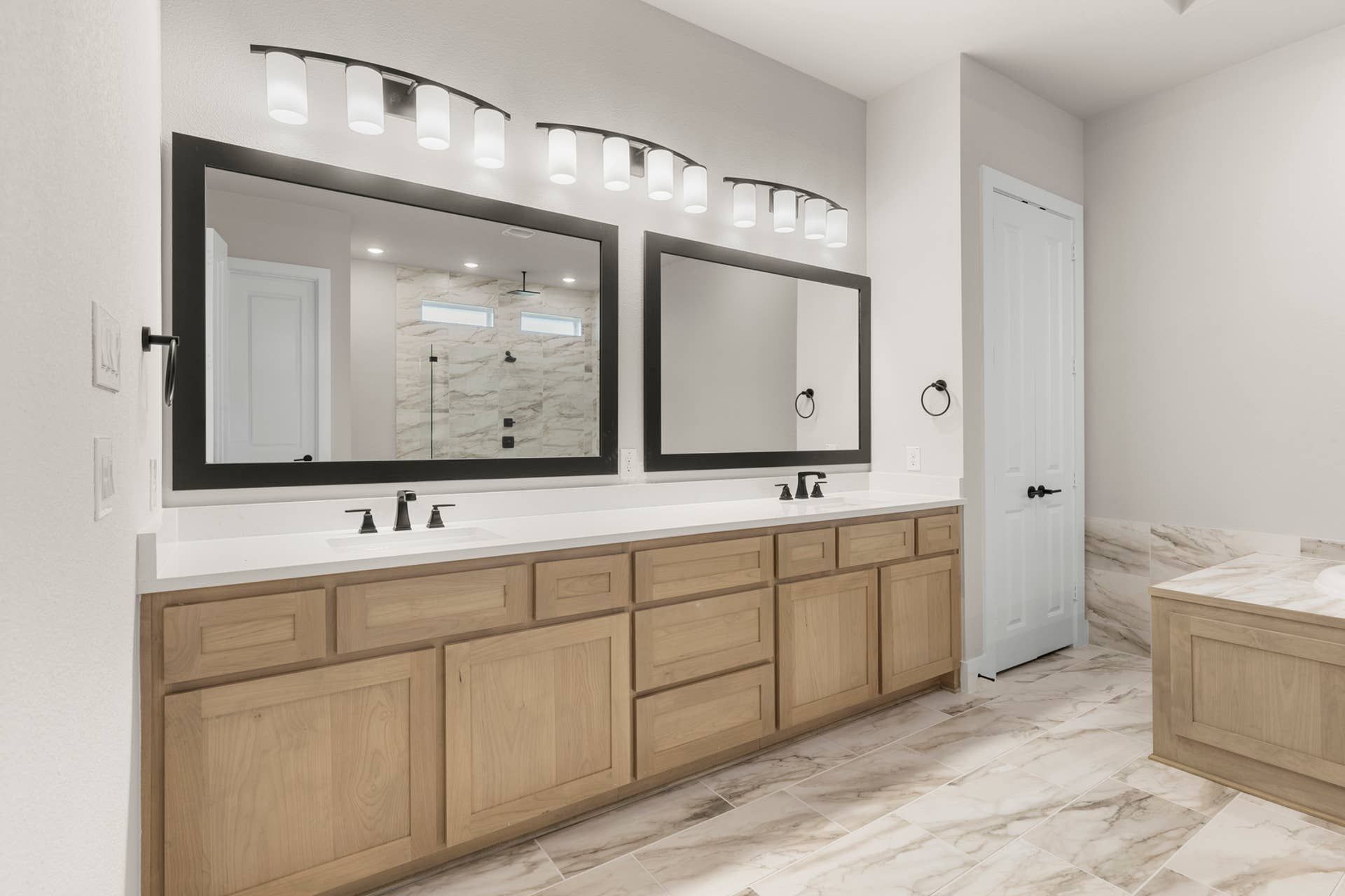 Luxurious bathroom with dual sinks, large mirrors, and elegant tile flooring.