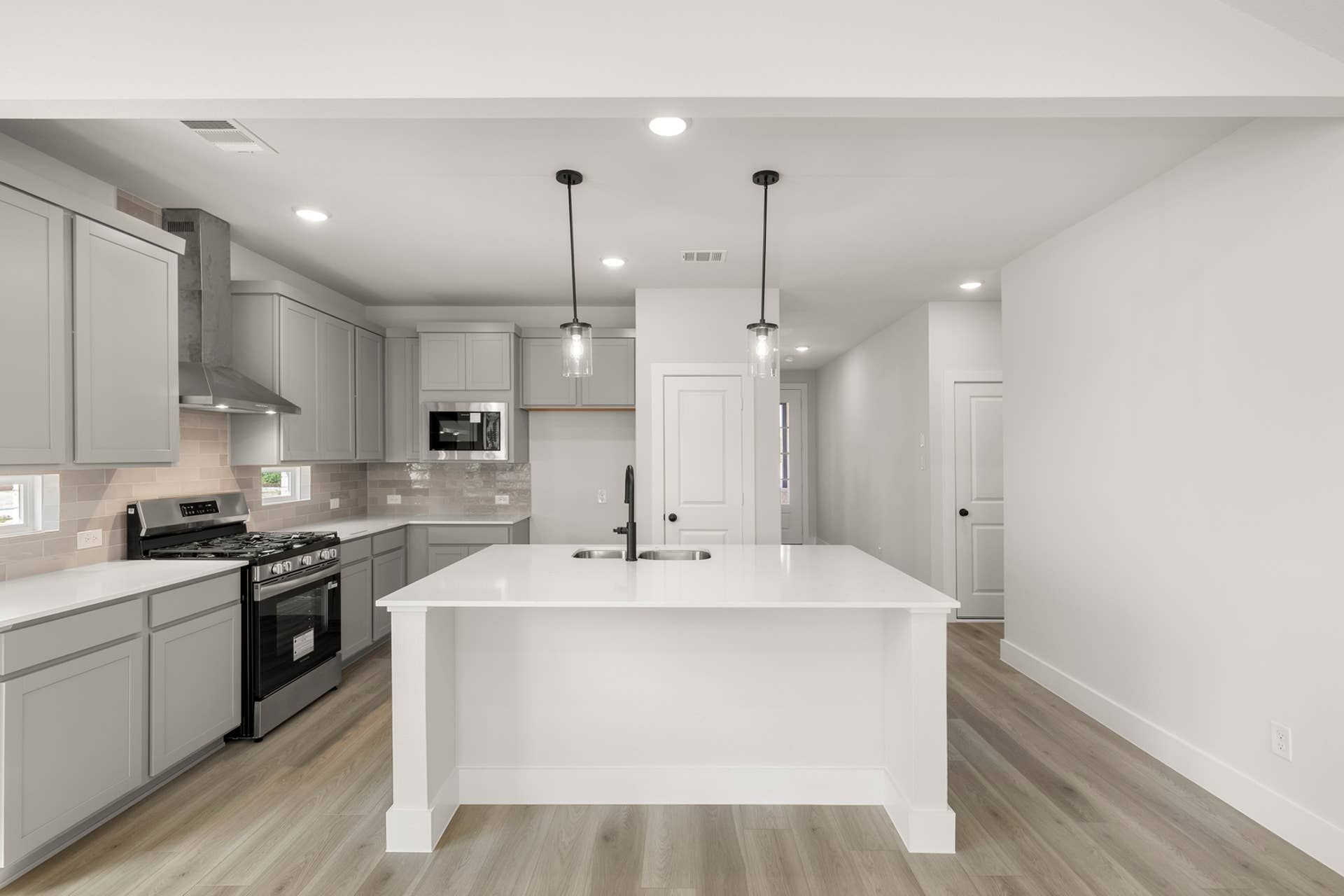 Modern kitchen with gray cabinets, island, and stainless steel appliances.