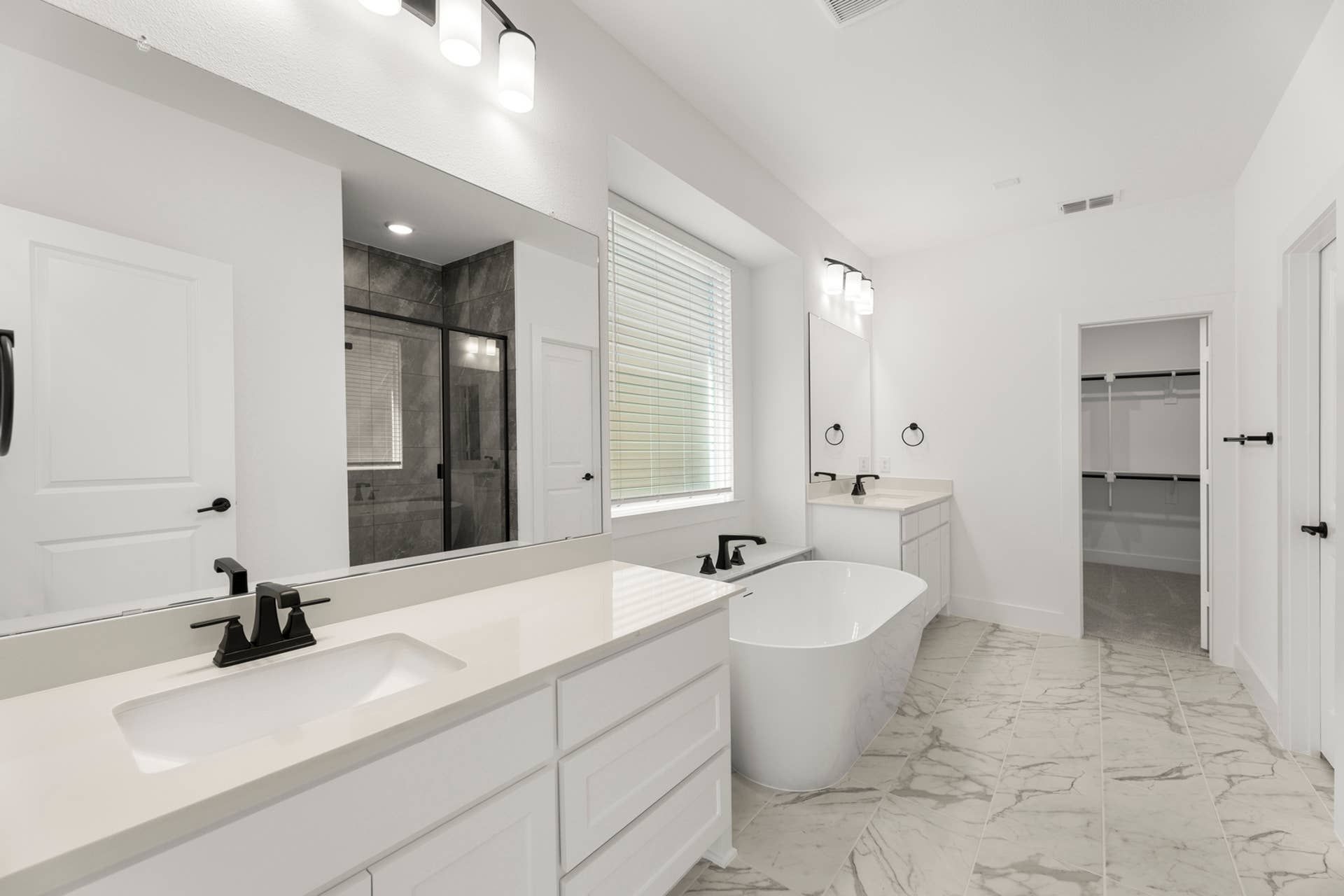 Luxurious bathroom with freestanding tub, dual vanity, and marble tile flooring.