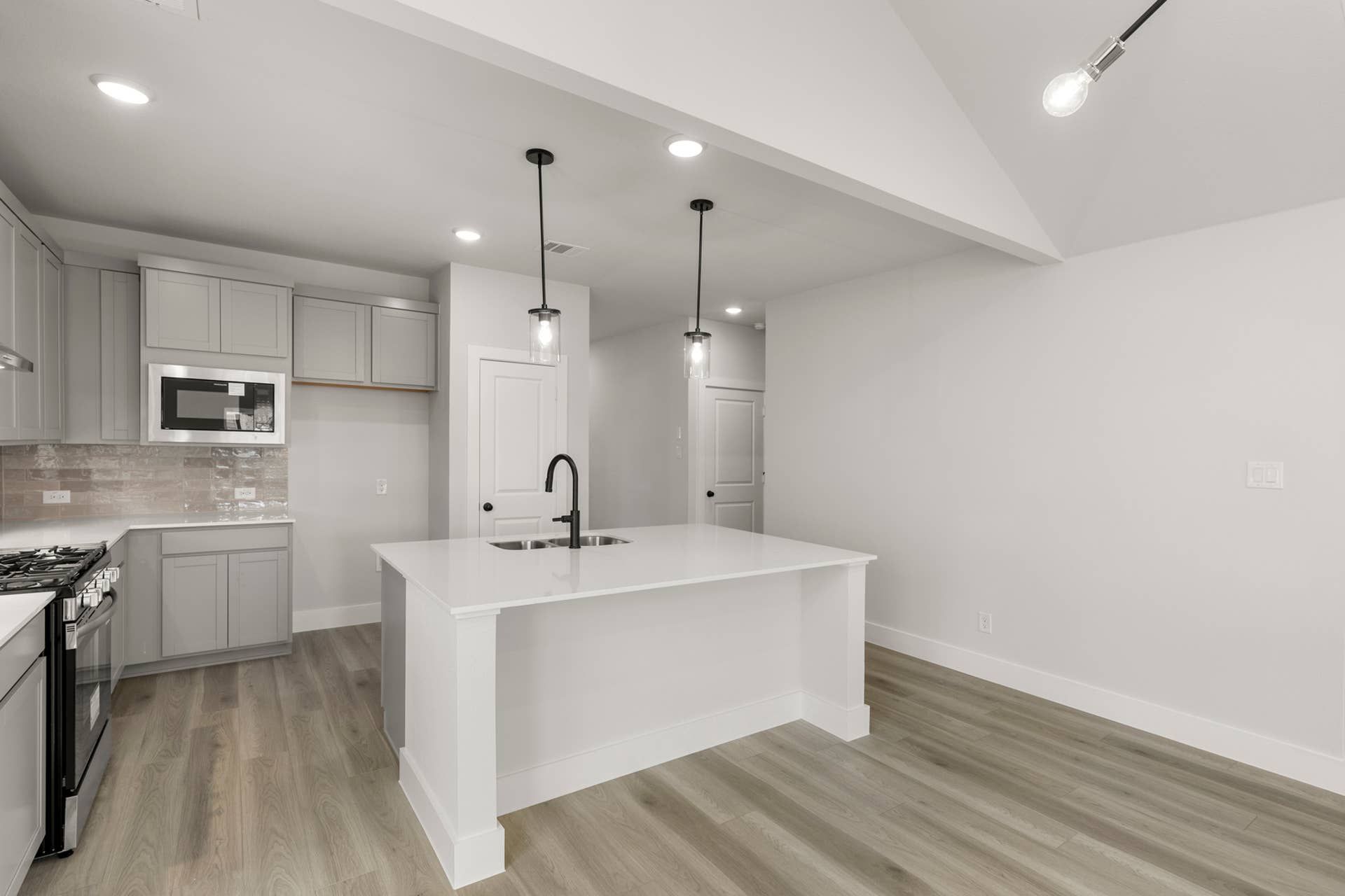 Modern kitchen with island, pendant lighting, and light wood flooring.