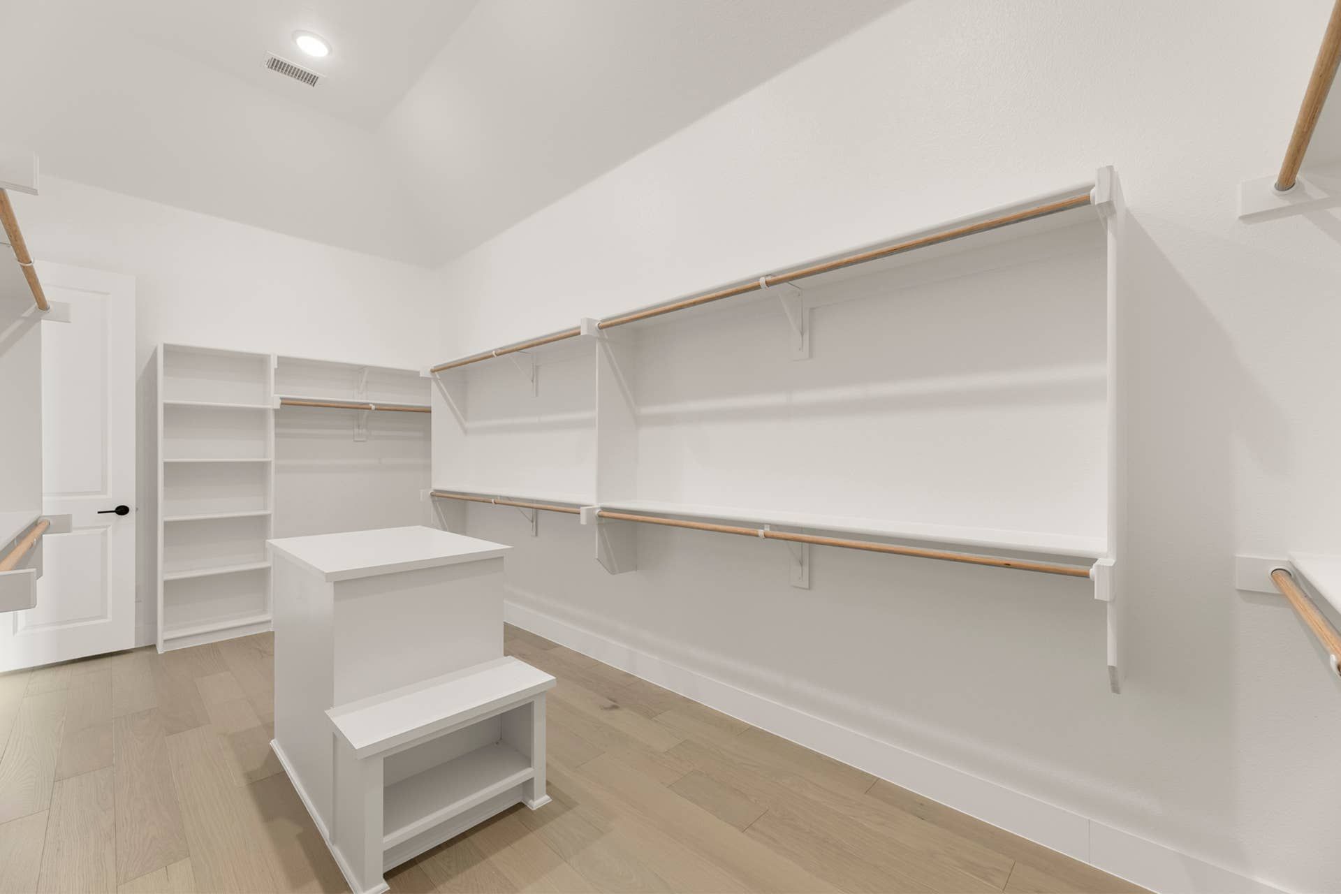 Spacious walk-in closet with wooden shelves and hanging rods.