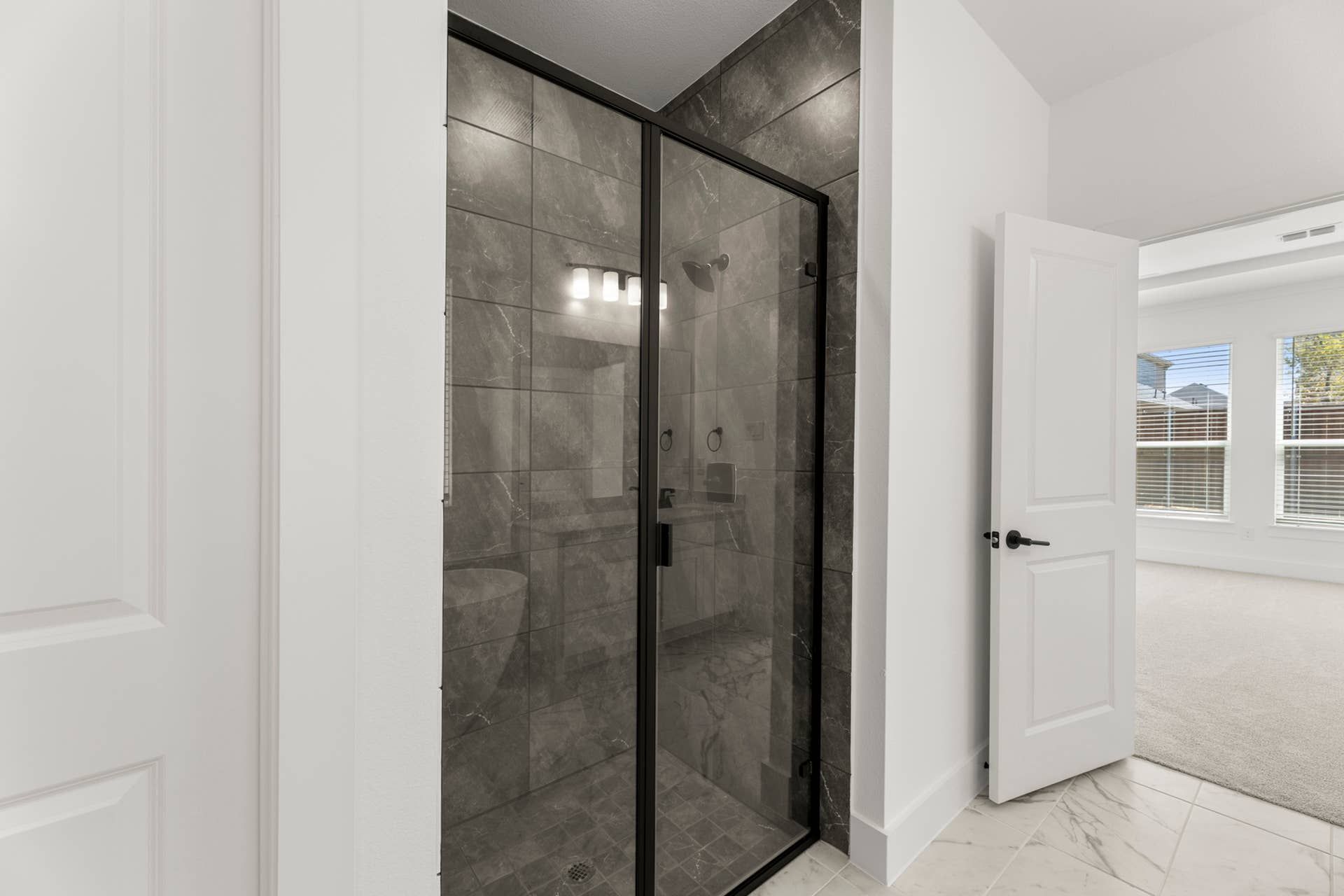Modern bathroom with glass-enclosed shower and marble flooring.