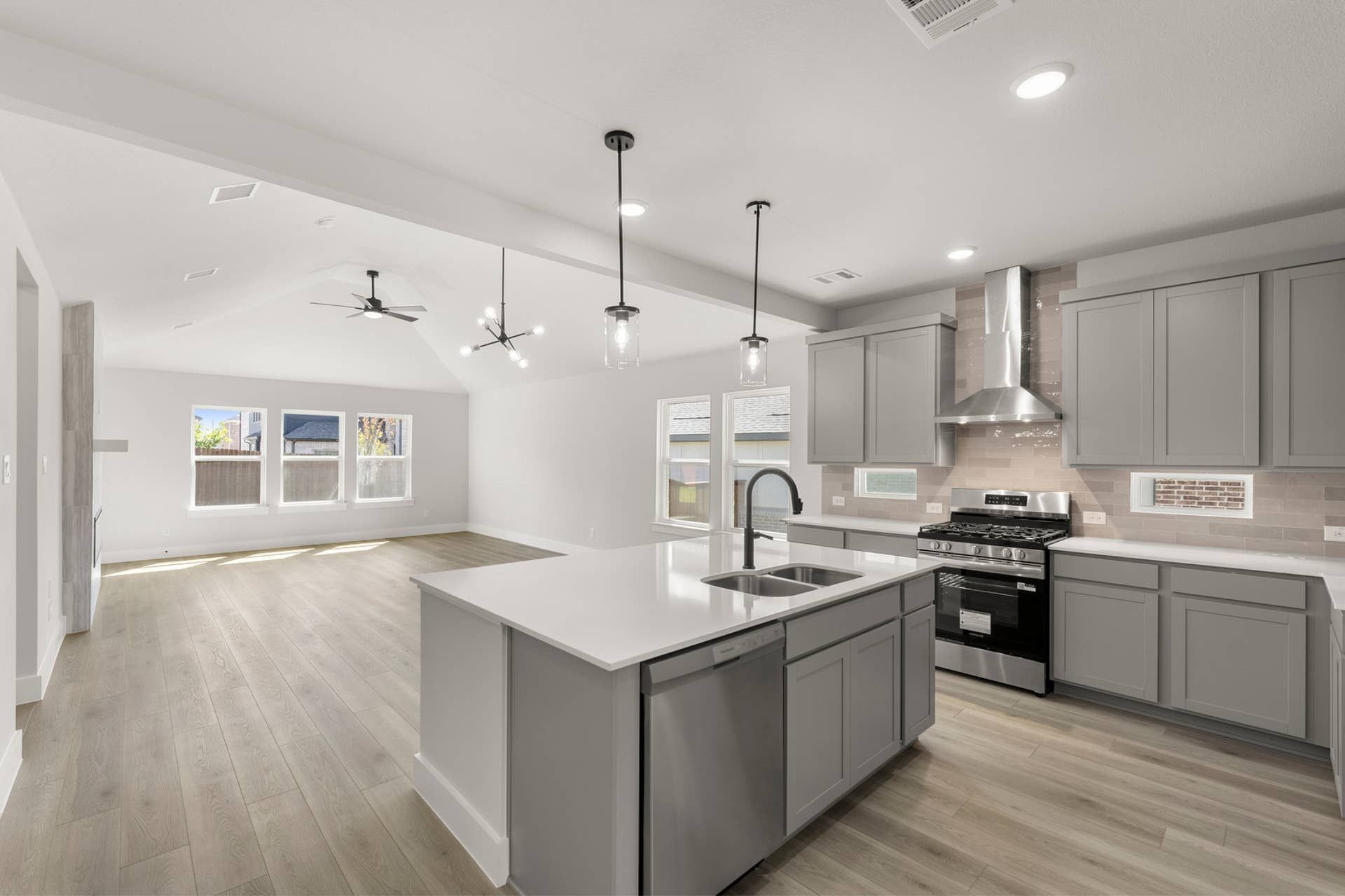 Modern kitchen with island, stainless steel appliances, and open living space.