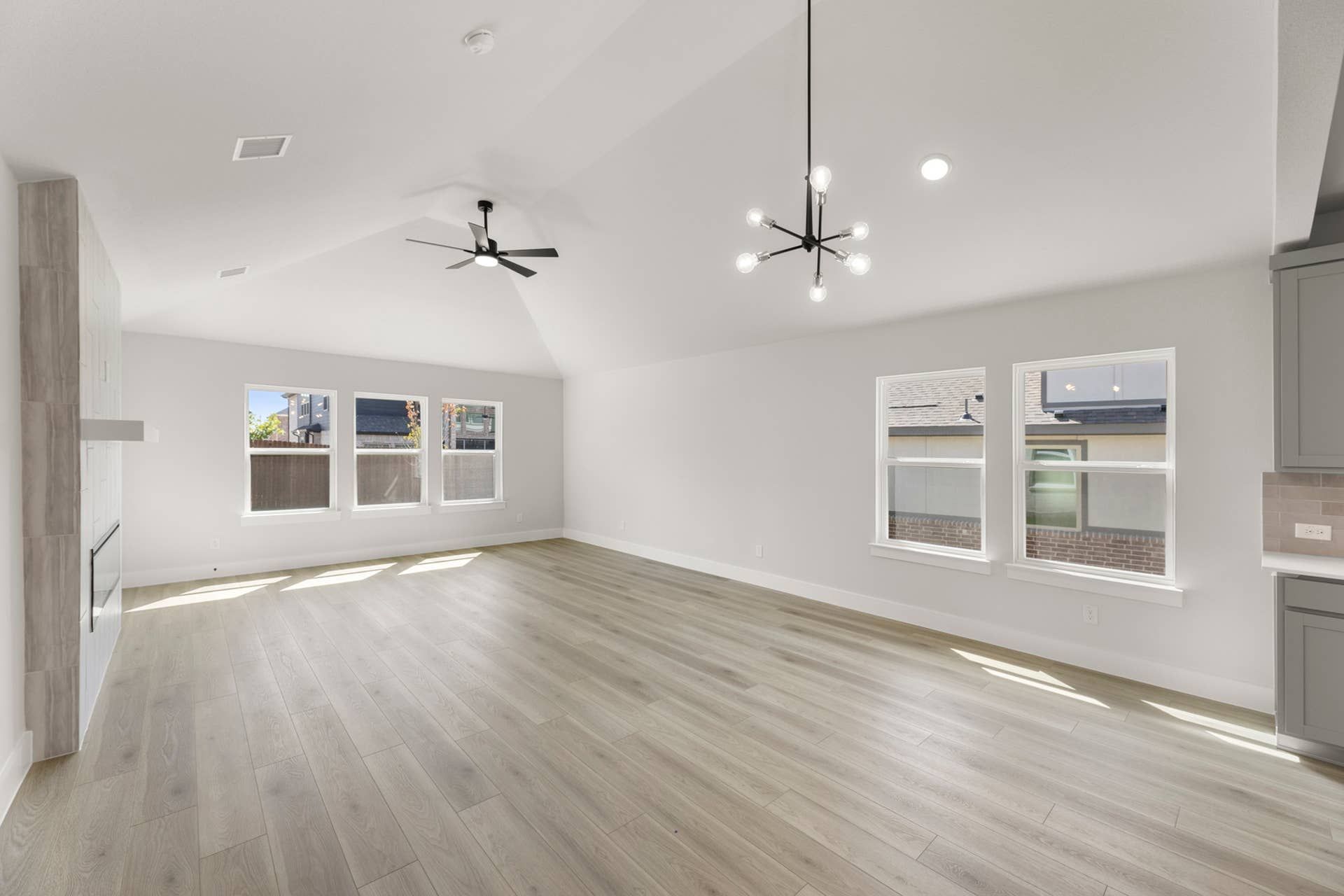 Spacious dining area with vaulted ceiling, modern lighting, and large windows.