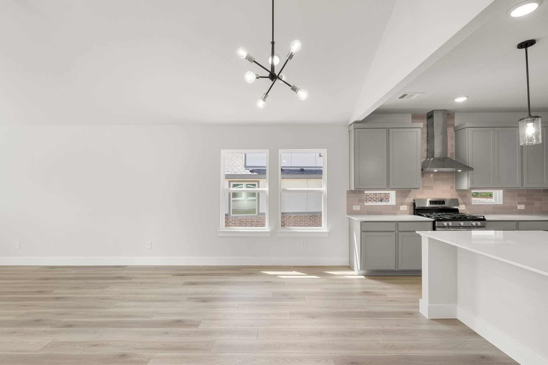Modern open-concept kitchen and dining area with sleek lighting and wood flooring.
