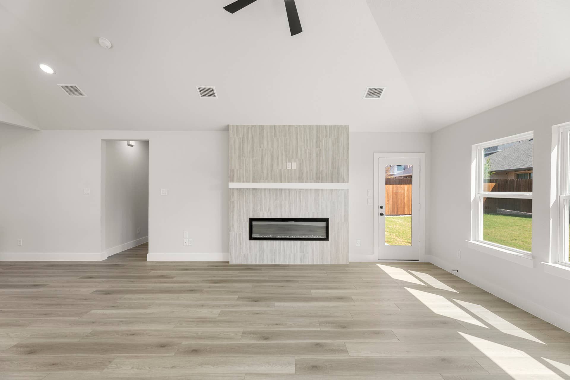 Modern living room with sleek fireplace, large windows, and light wood flooring.