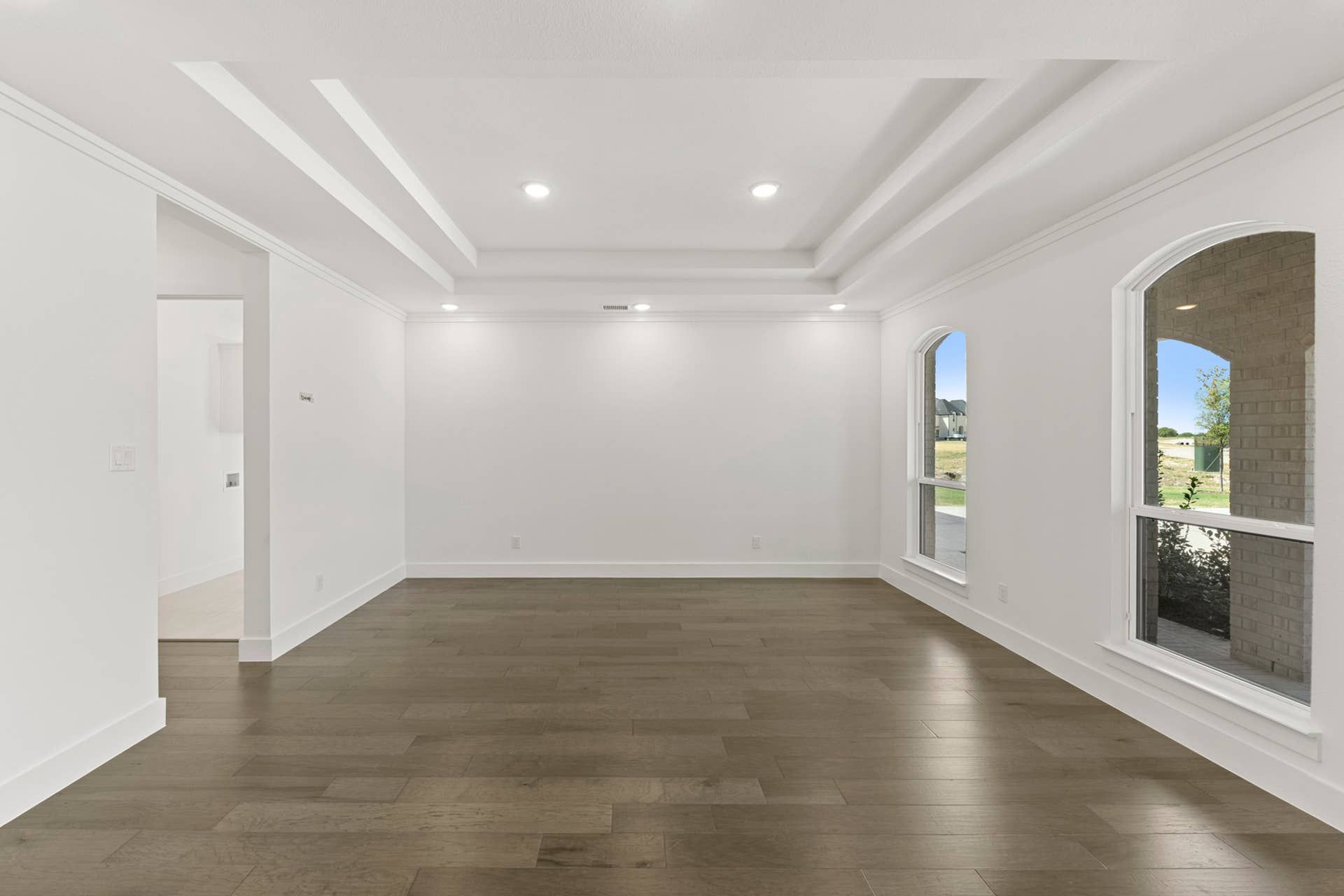 Spacious dining area with tray ceiling and large windows.
