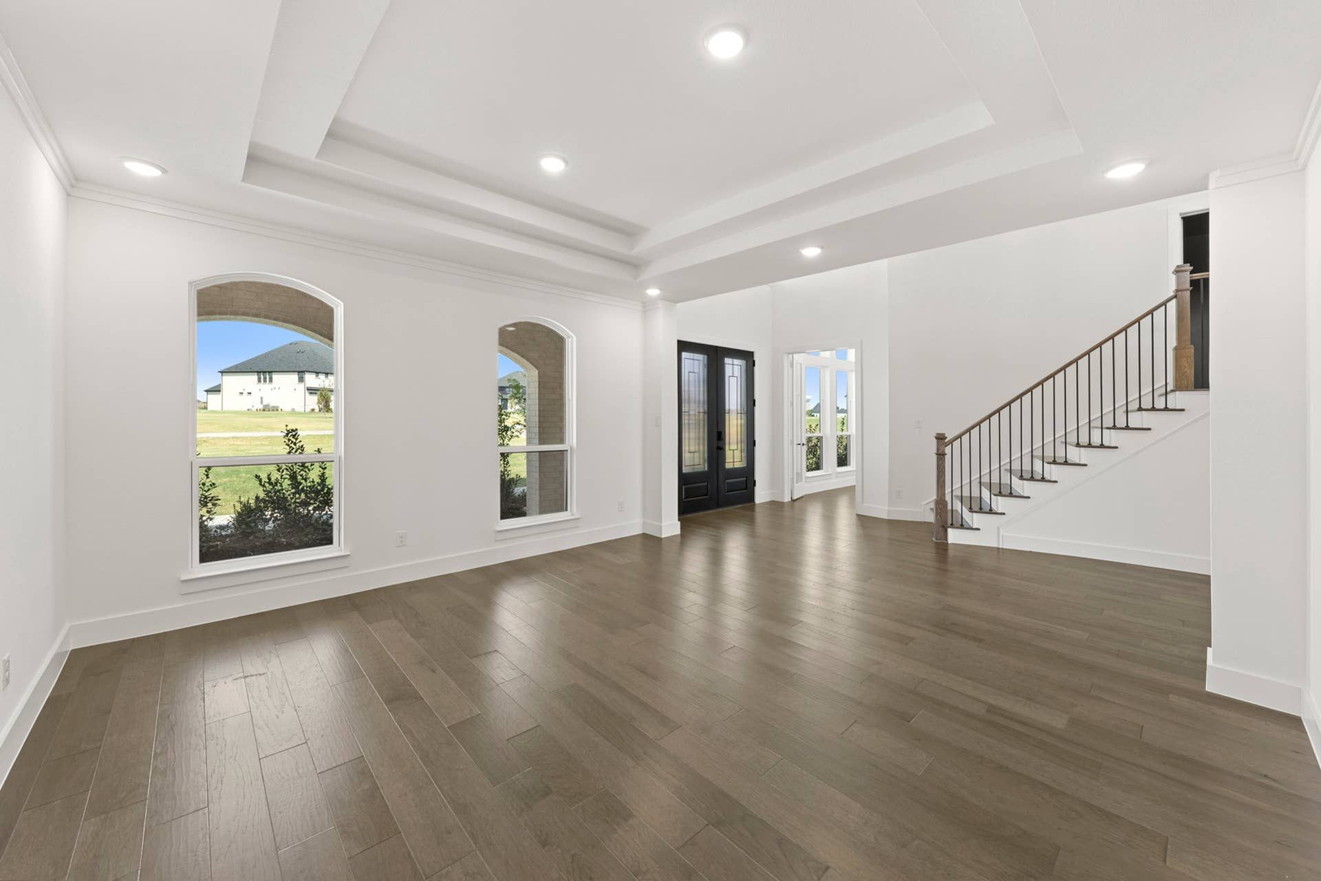 Spacious dining area with hardwood floors and elegant staircase.