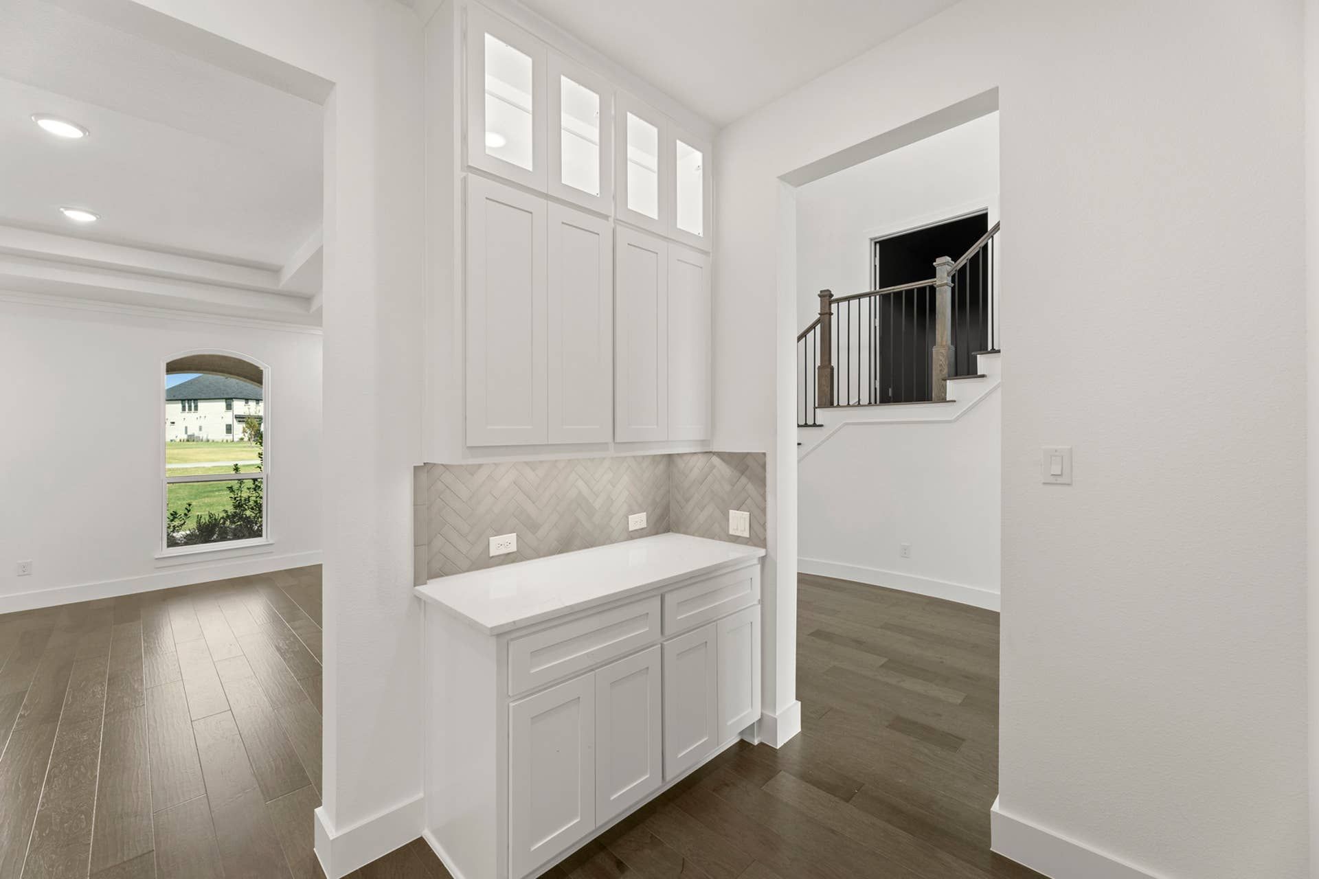 Spacious pantry with white cabinetry and herringbone backsplash in modern interior.