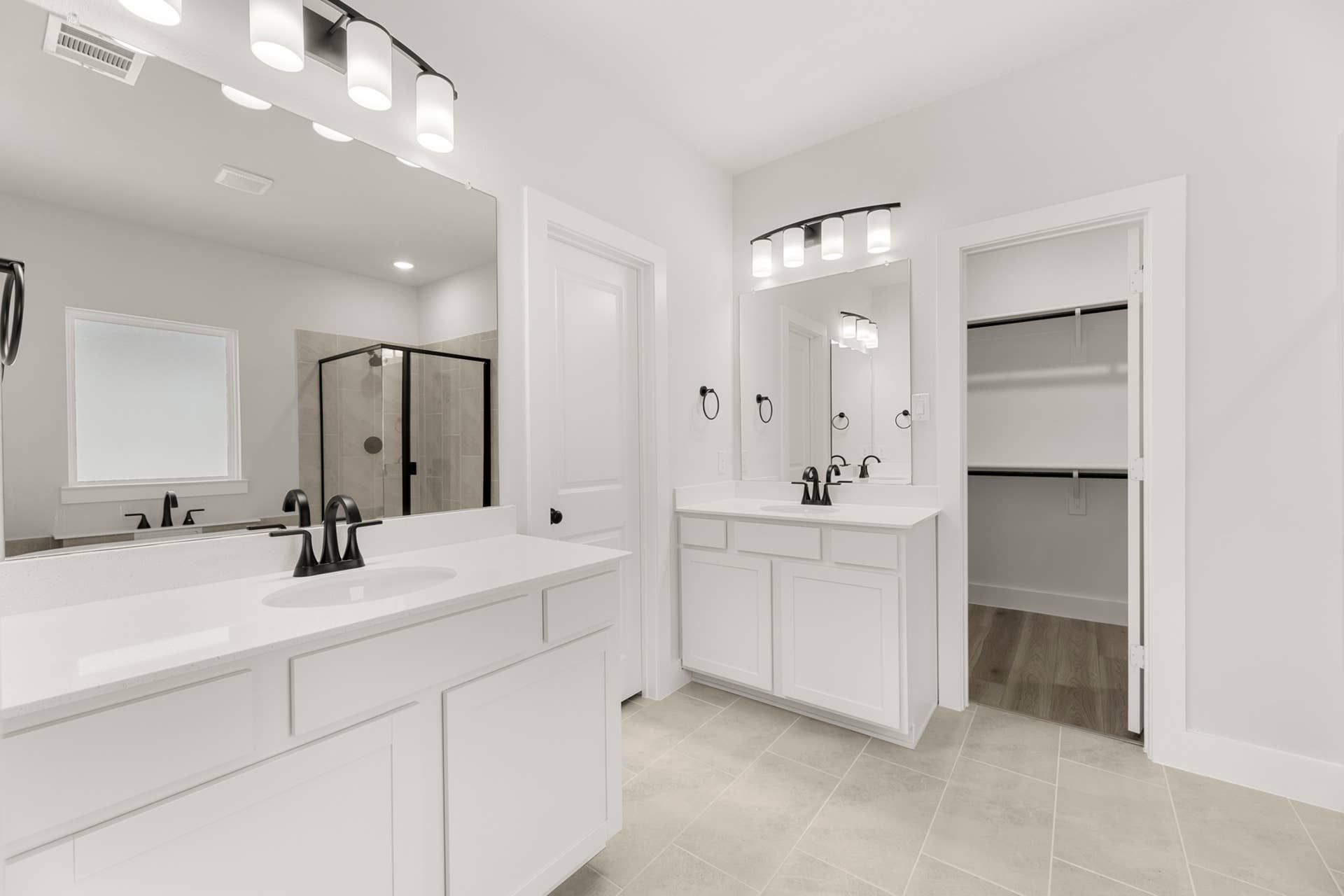 Modern bathroom with dual vanities, glass shower, and walk-in closet.