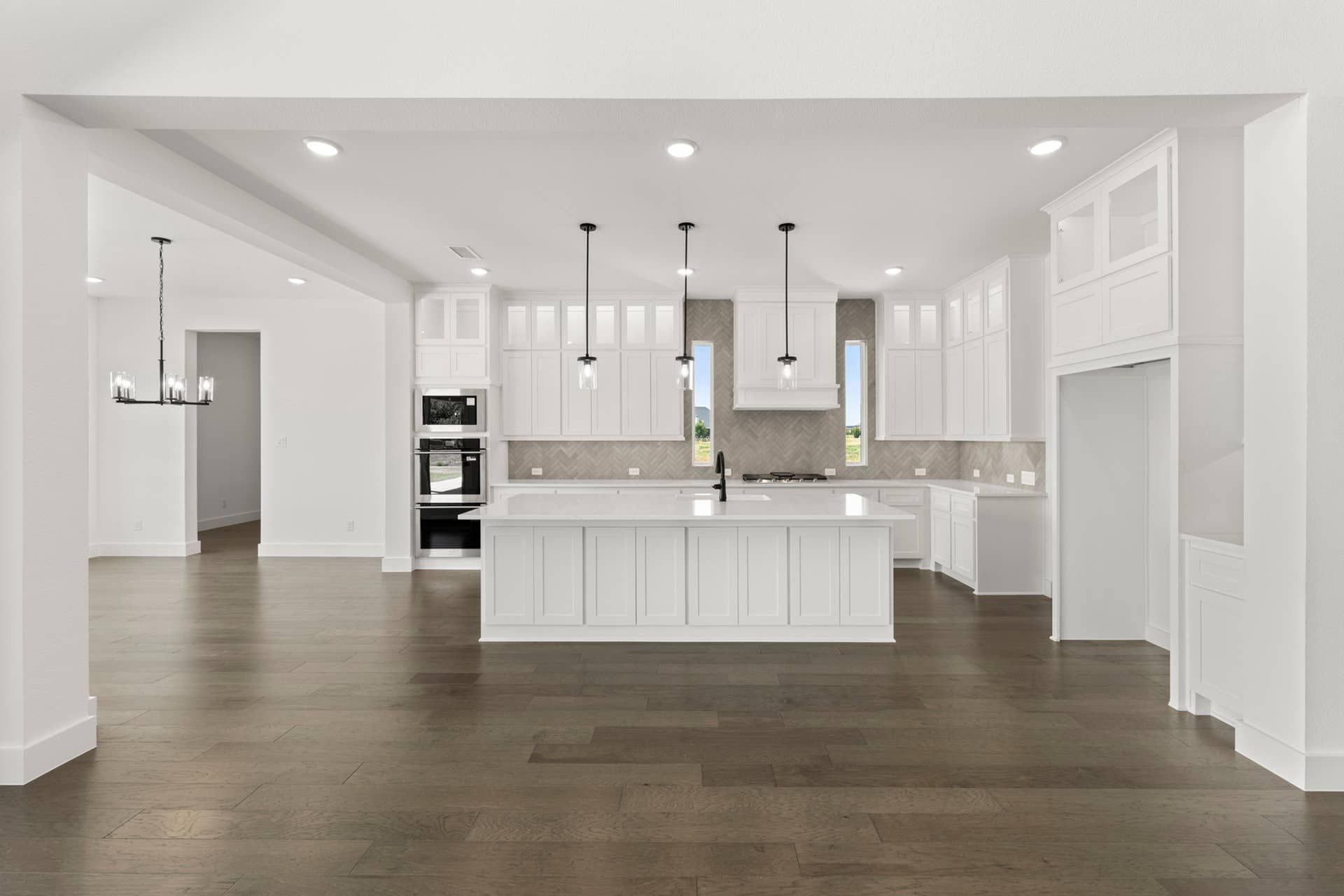 Modern kitchen with white cabinetry, island, and pendant lighting.