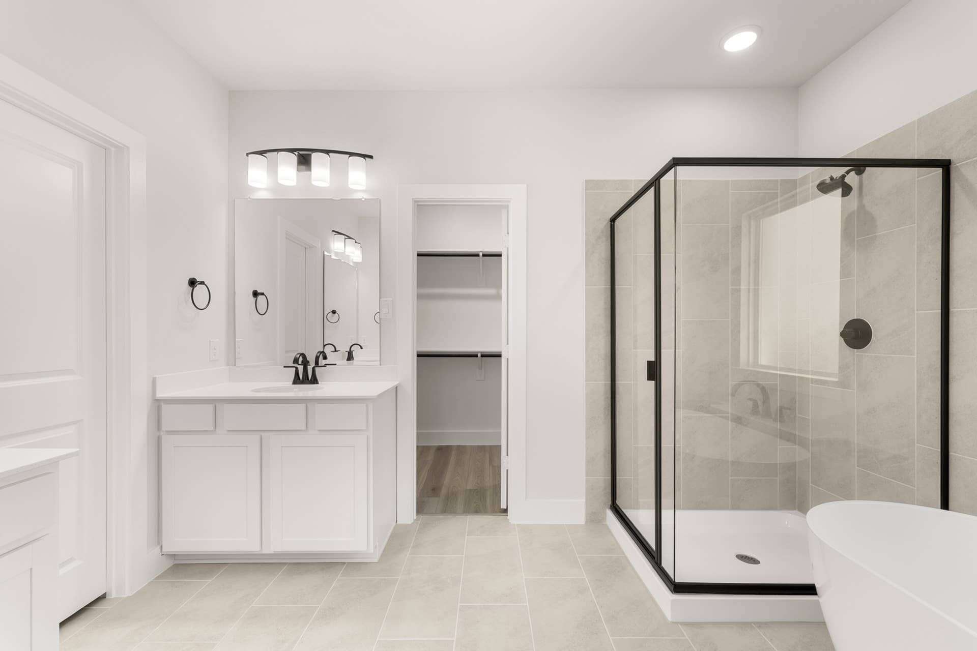 Modern bathroom with glass shower, white vanity, and spacious walk-in closet.