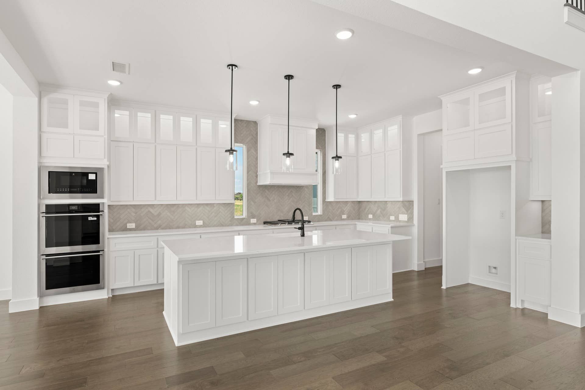 Spacious modern kitchen with white cabinetry, large island, and pendant lighting.