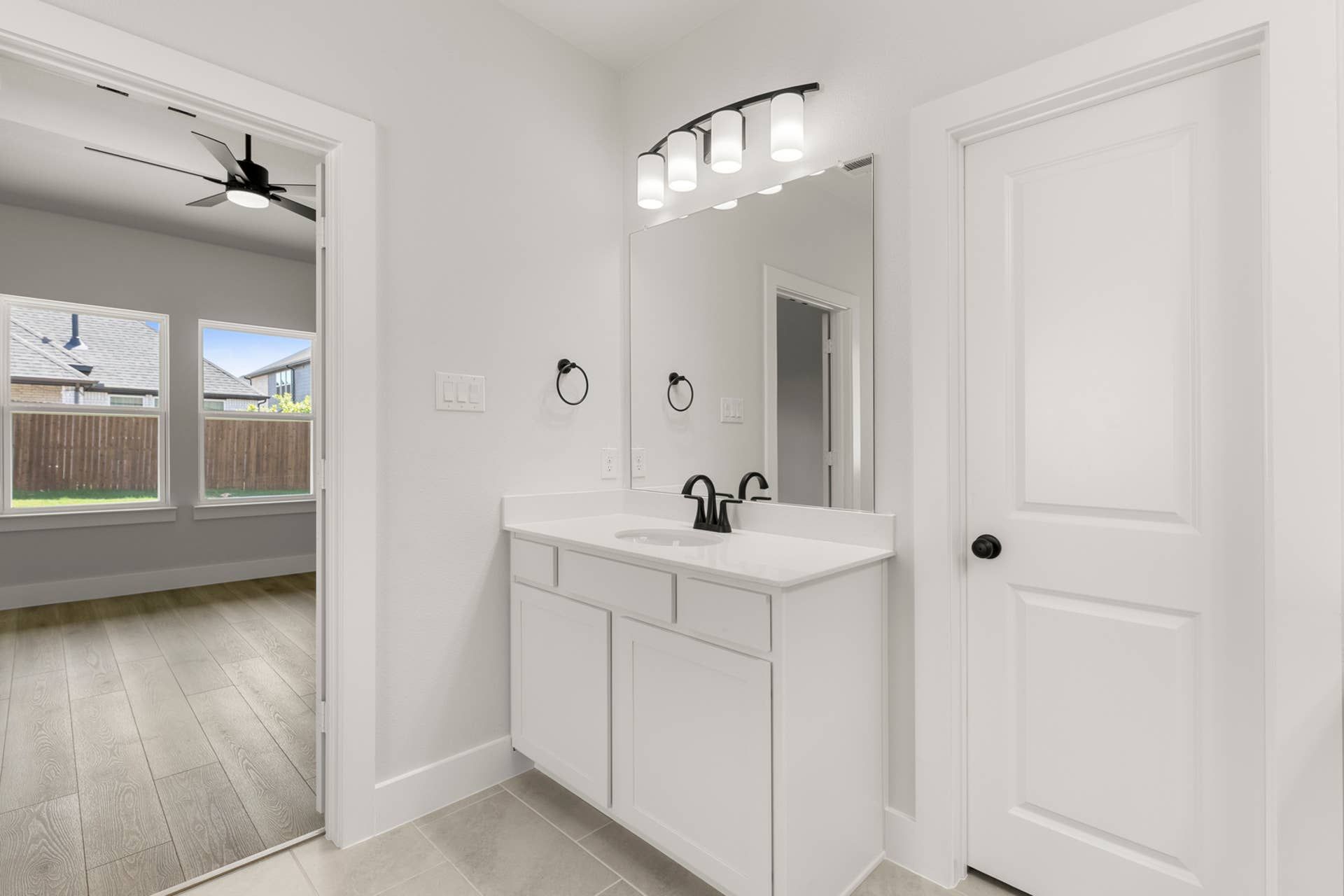 Modern bathroom with white vanity, large mirror, and black fixtures.
