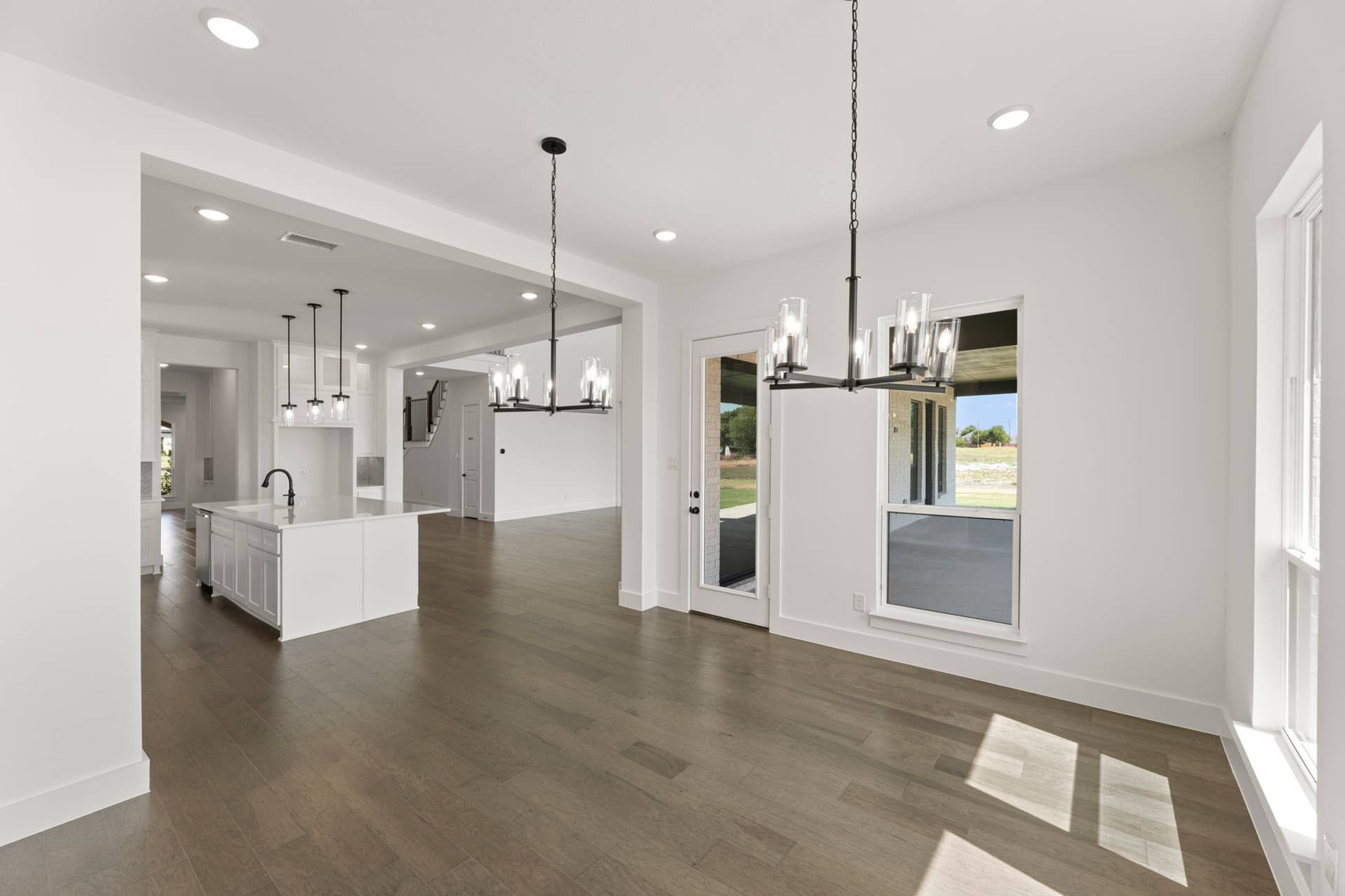 Modern open-concept kitchen and dining area with elegant lighting fixtures.