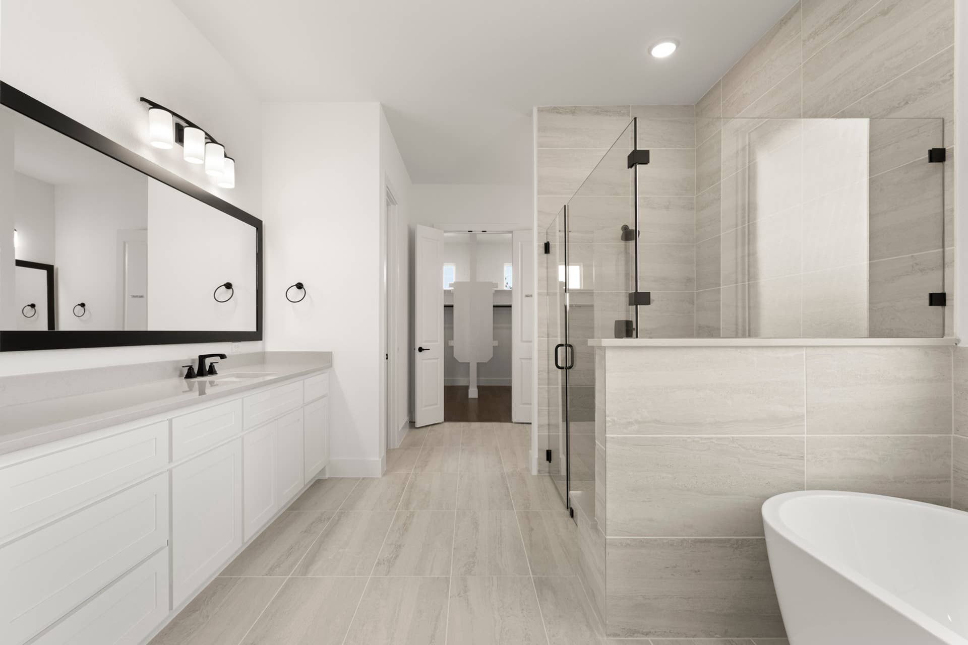 Spacious modern bathroom with glass shower, freestanding tub, and large mirror.