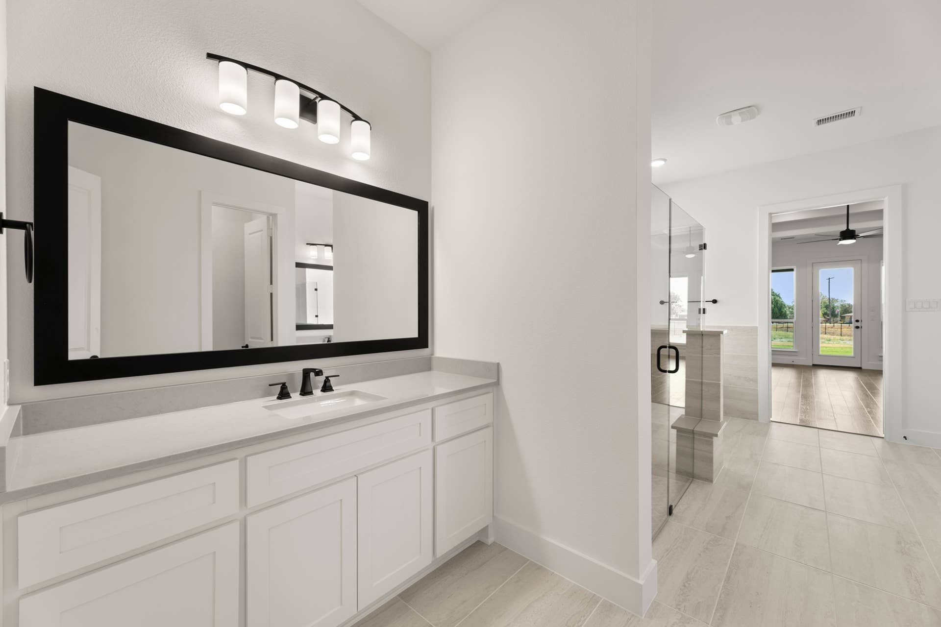 Modern bathroom with large mirror, sleek vanity, and glass-enclosed shower.
