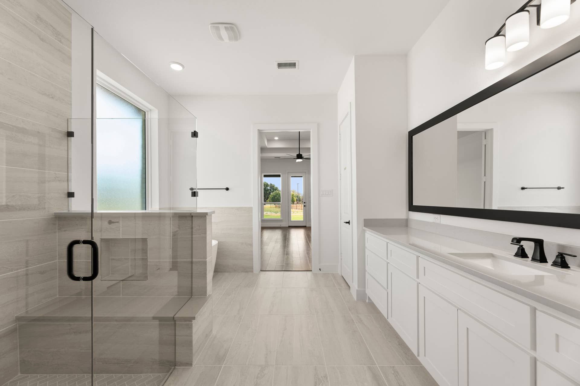 Modern bathroom with glass shower, dual sinks, and large mirror.