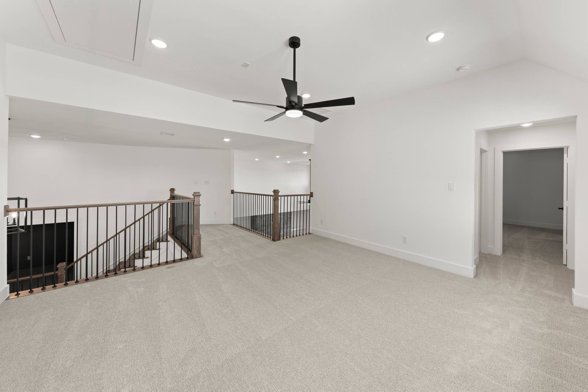 Spacious interior with modern ceiling fan and carpeted floor.