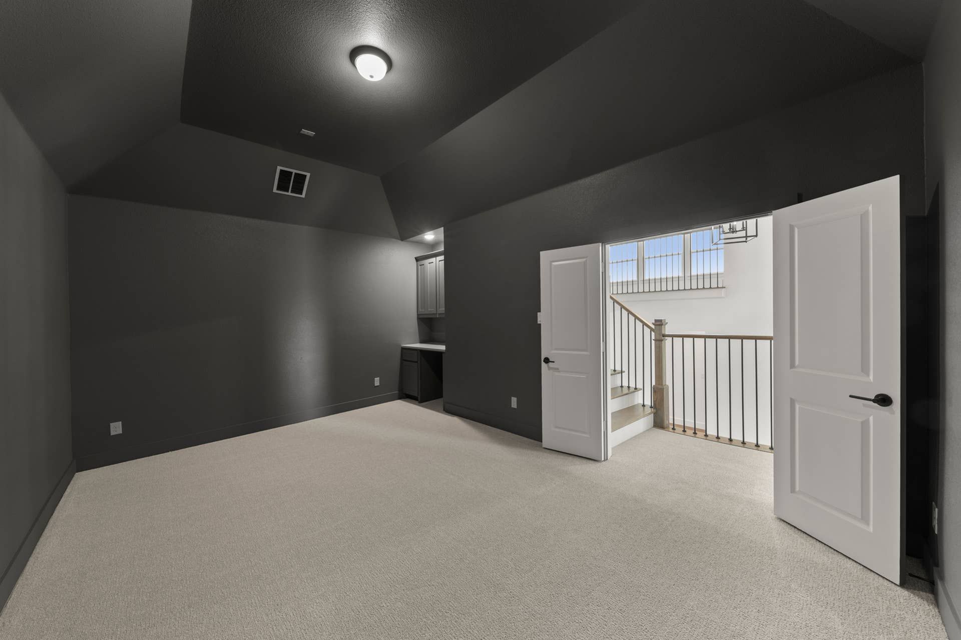 Spacious interior room with dark walls, open doors, and carpeted flooring.