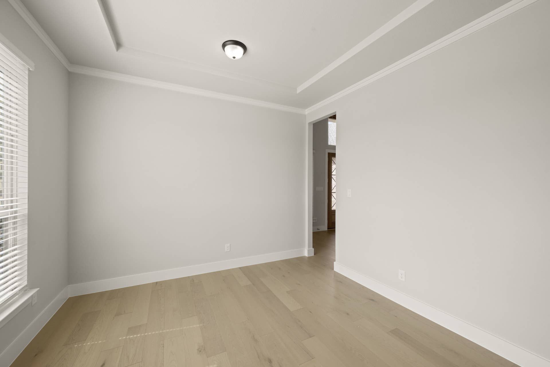 Bright dining room with light hardwood floors and crown molding.