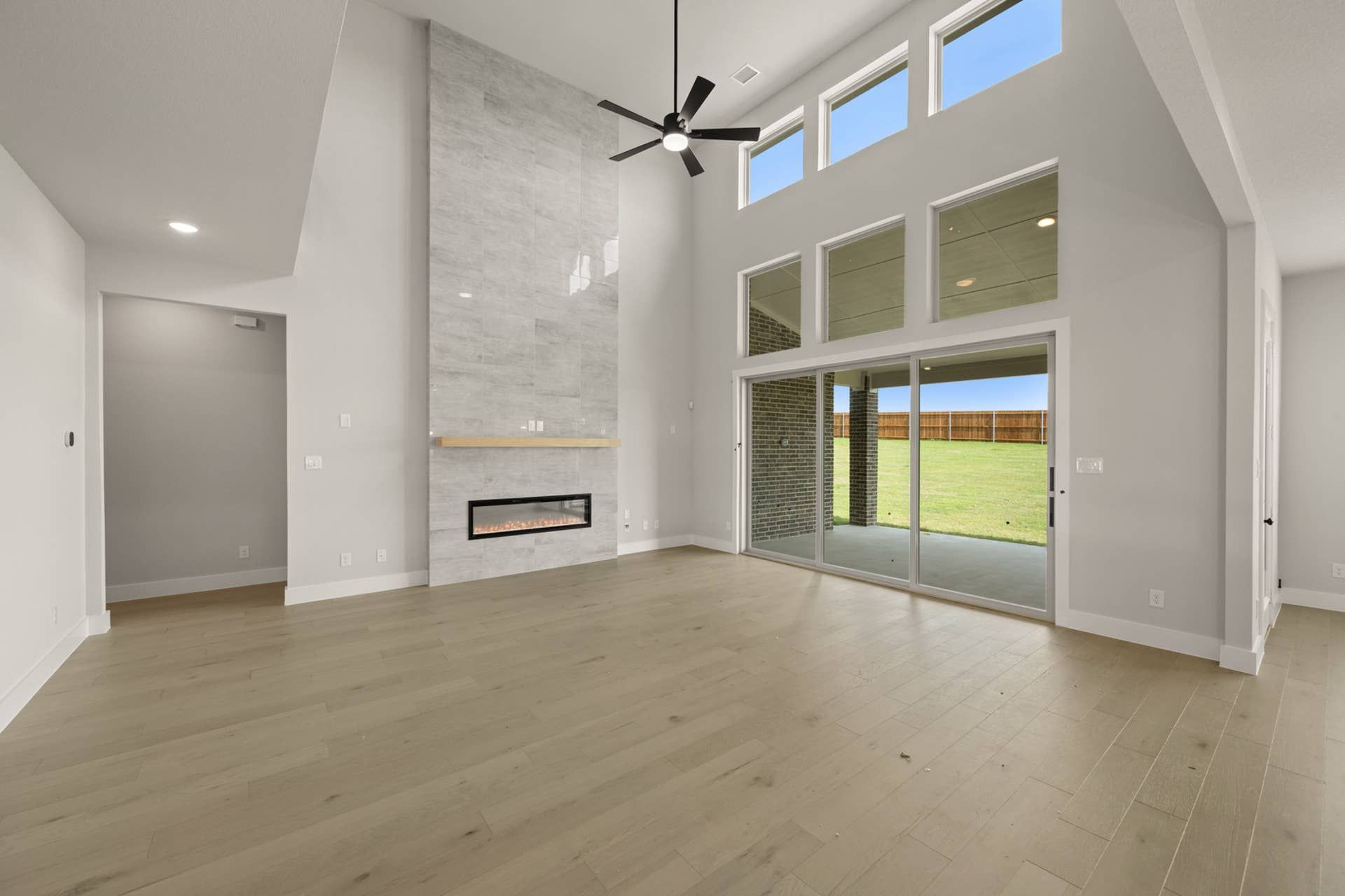 Spacious living room with high ceiling, modern fireplace, and large windows.