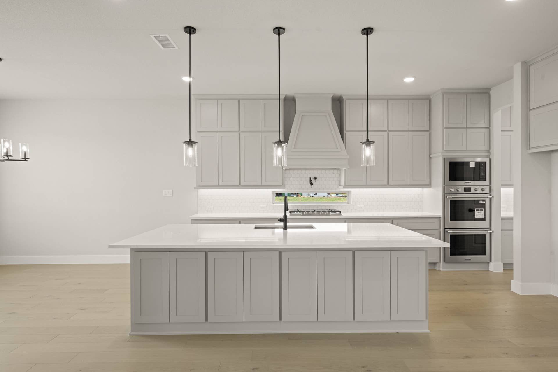 Modern kitchen with white cabinetry, island, and pendant lighting.