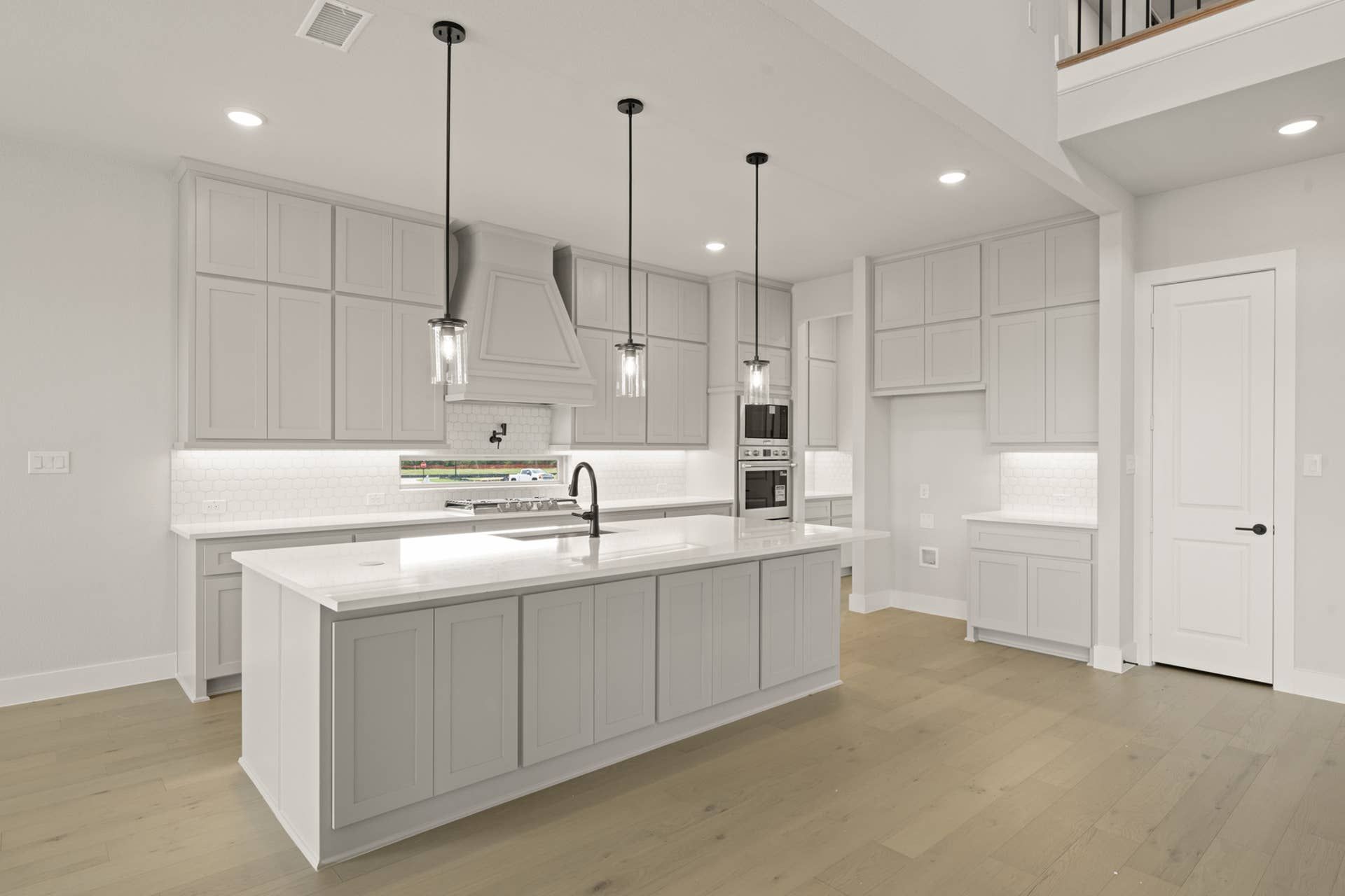 Modern kitchen with white cabinetry, island, and pendant lighting.
