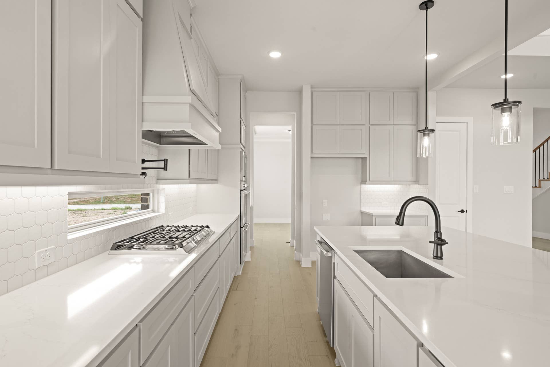 Modern kitchen with white cabinets, island, and pendant lighting.