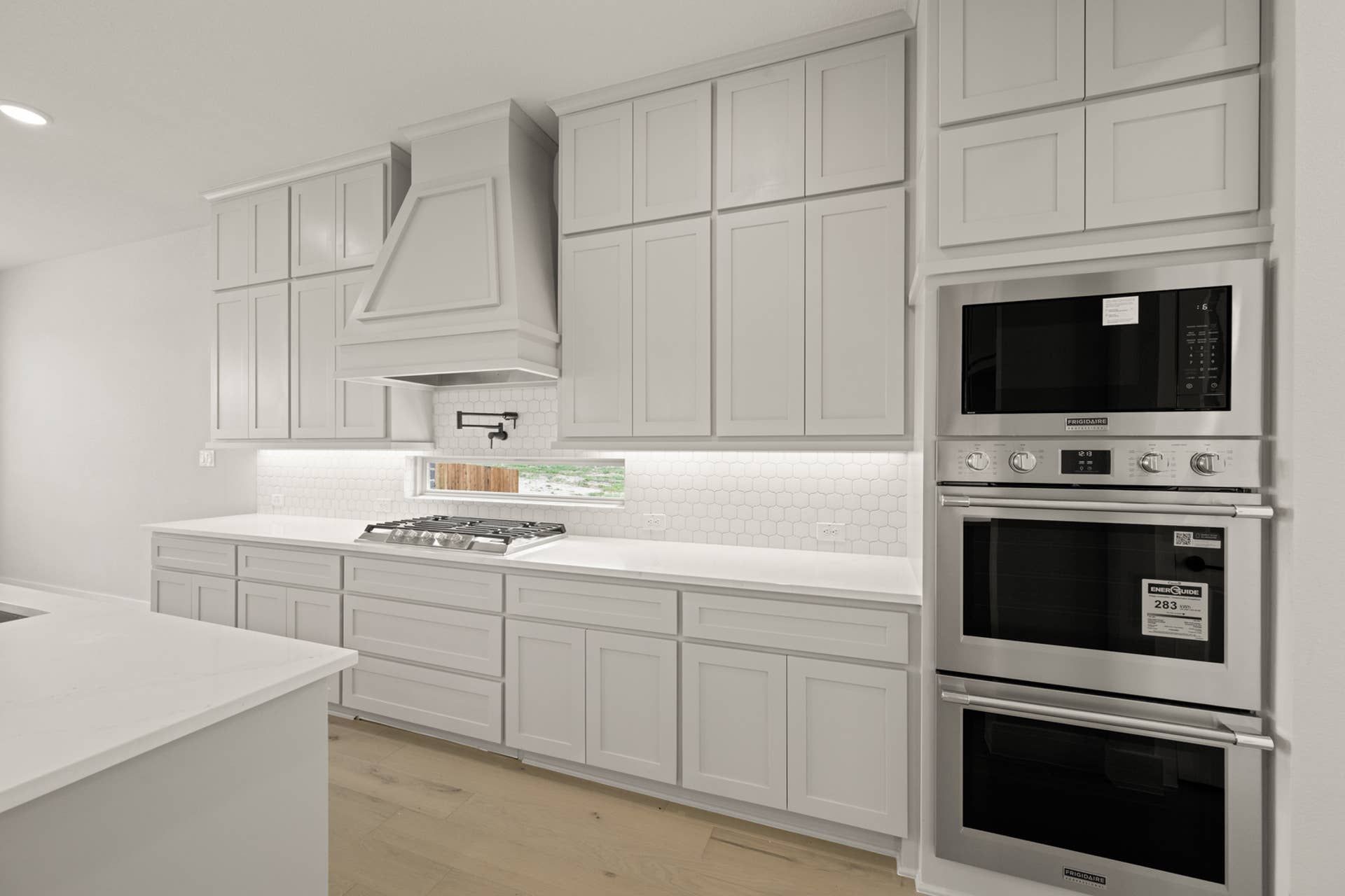 Modern kitchen with white cabinetry, stainless steel appliances, and hexagonal tile backsplash.
